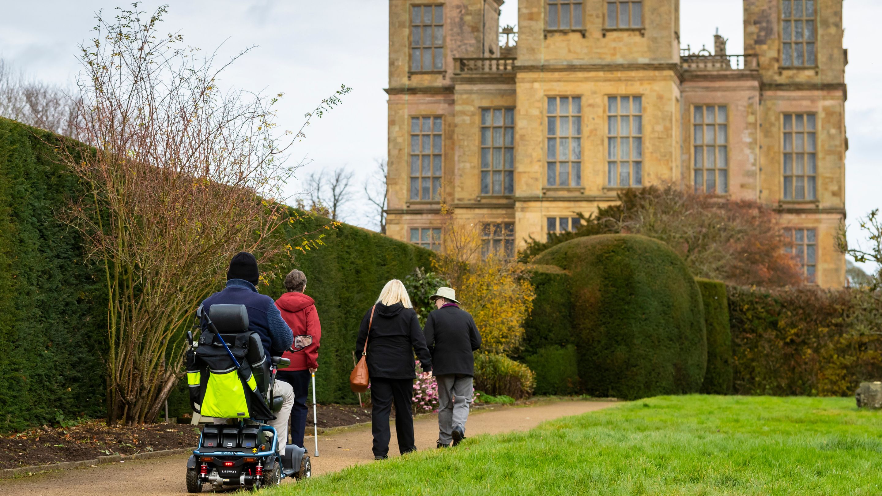 Visitors with reduced mobility exploring the garden in autumn at Hardwick, Derbyshire