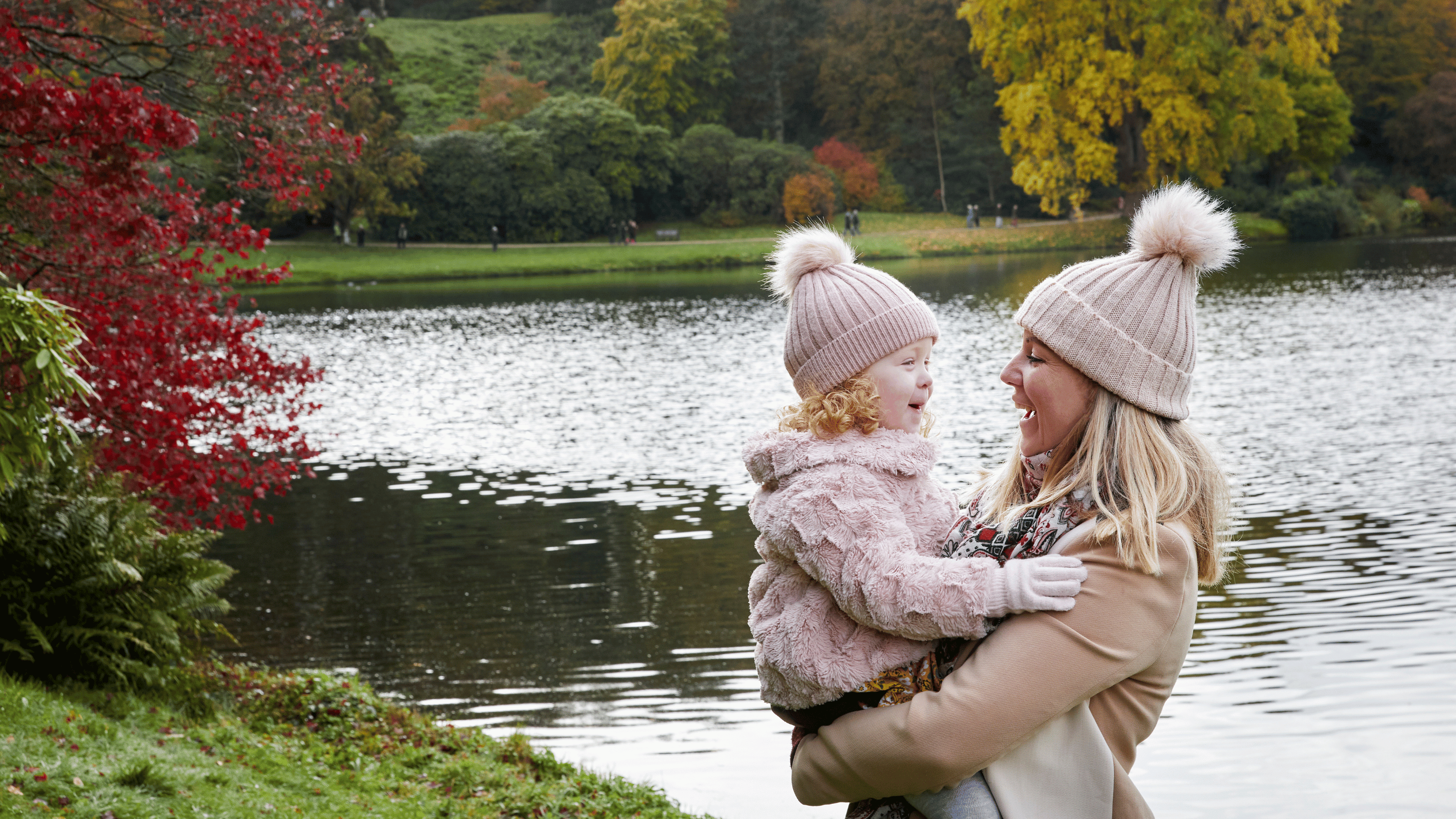 Mother and daughter posing for a photo in front of a lake