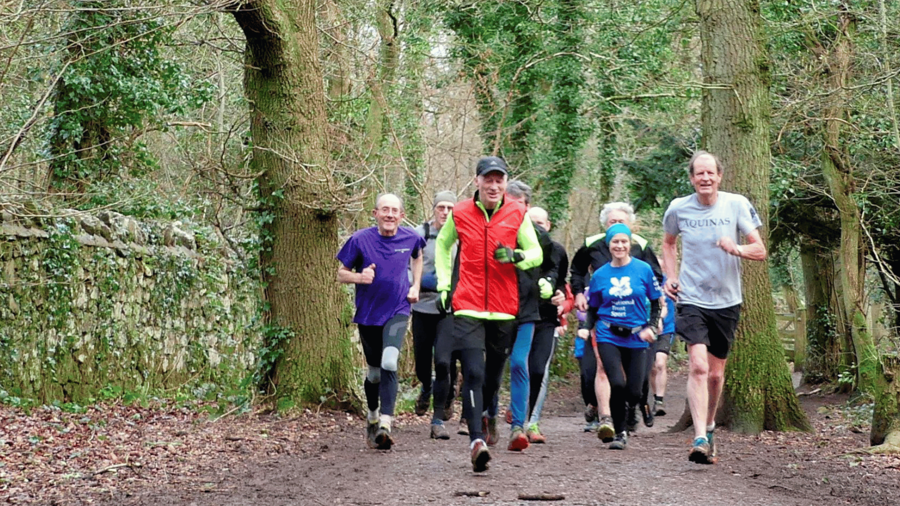 A group of people in brightly colour clothes running through the woods