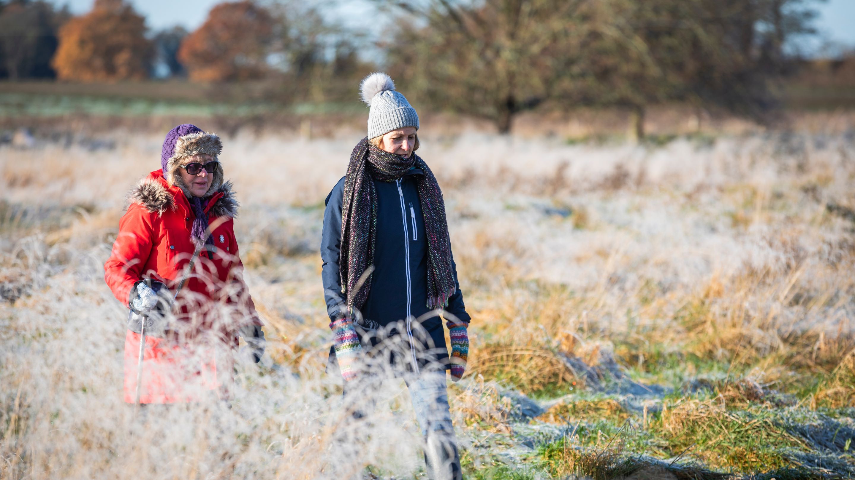 Two visitors enjoying a winter walk across grassland