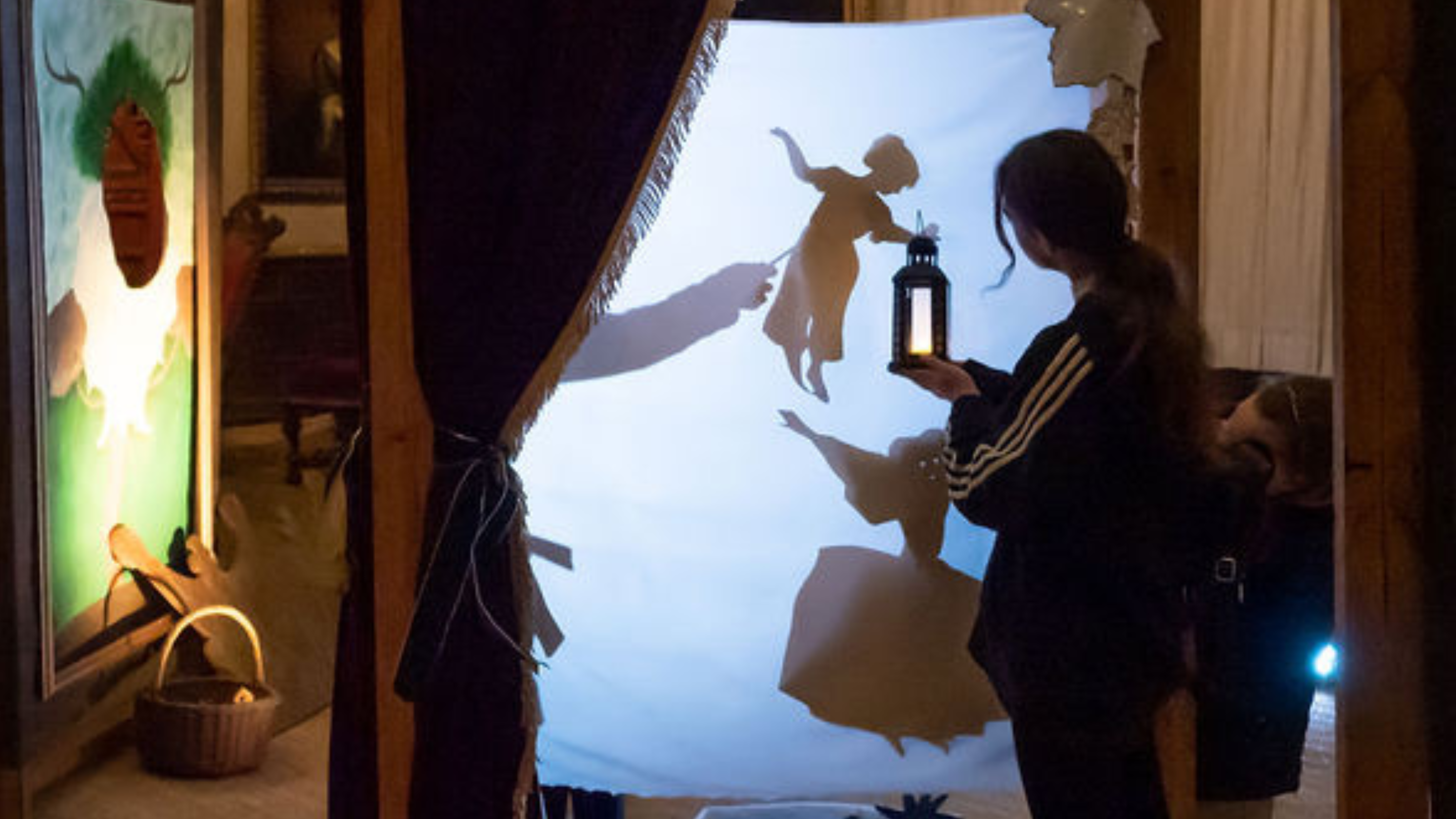Visitor holding up a lantern to the shadow puppets in the Long Gallery at Hardwick, Derbyshire