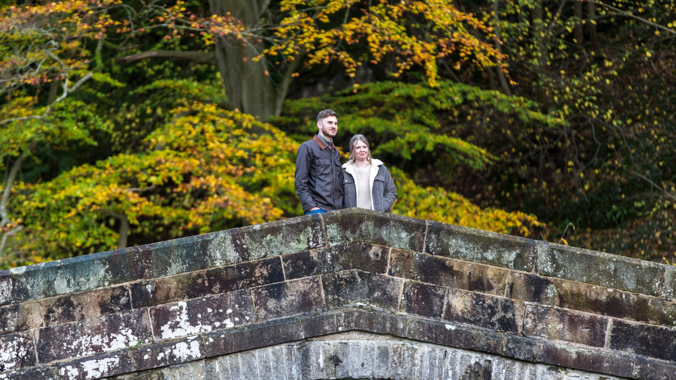 Couple stood on the bridge across the River Manifold at Ilam Park, Derbyshire