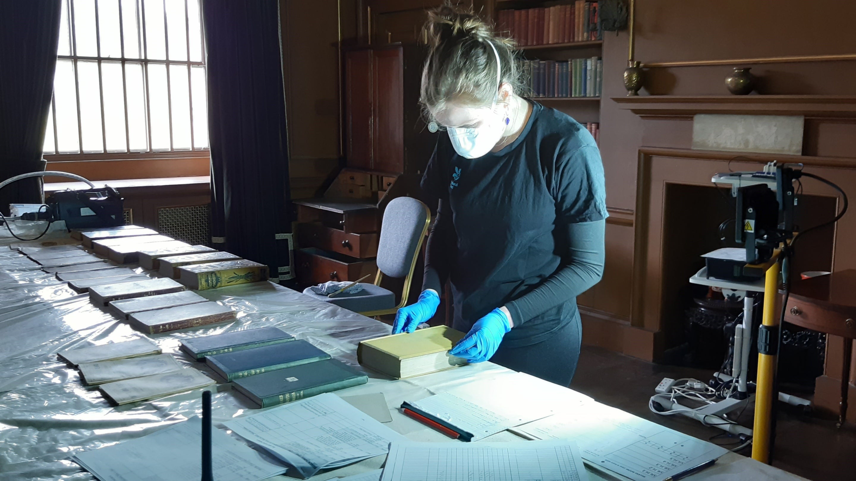 A member of the house team inspects books at Kedleston Hall