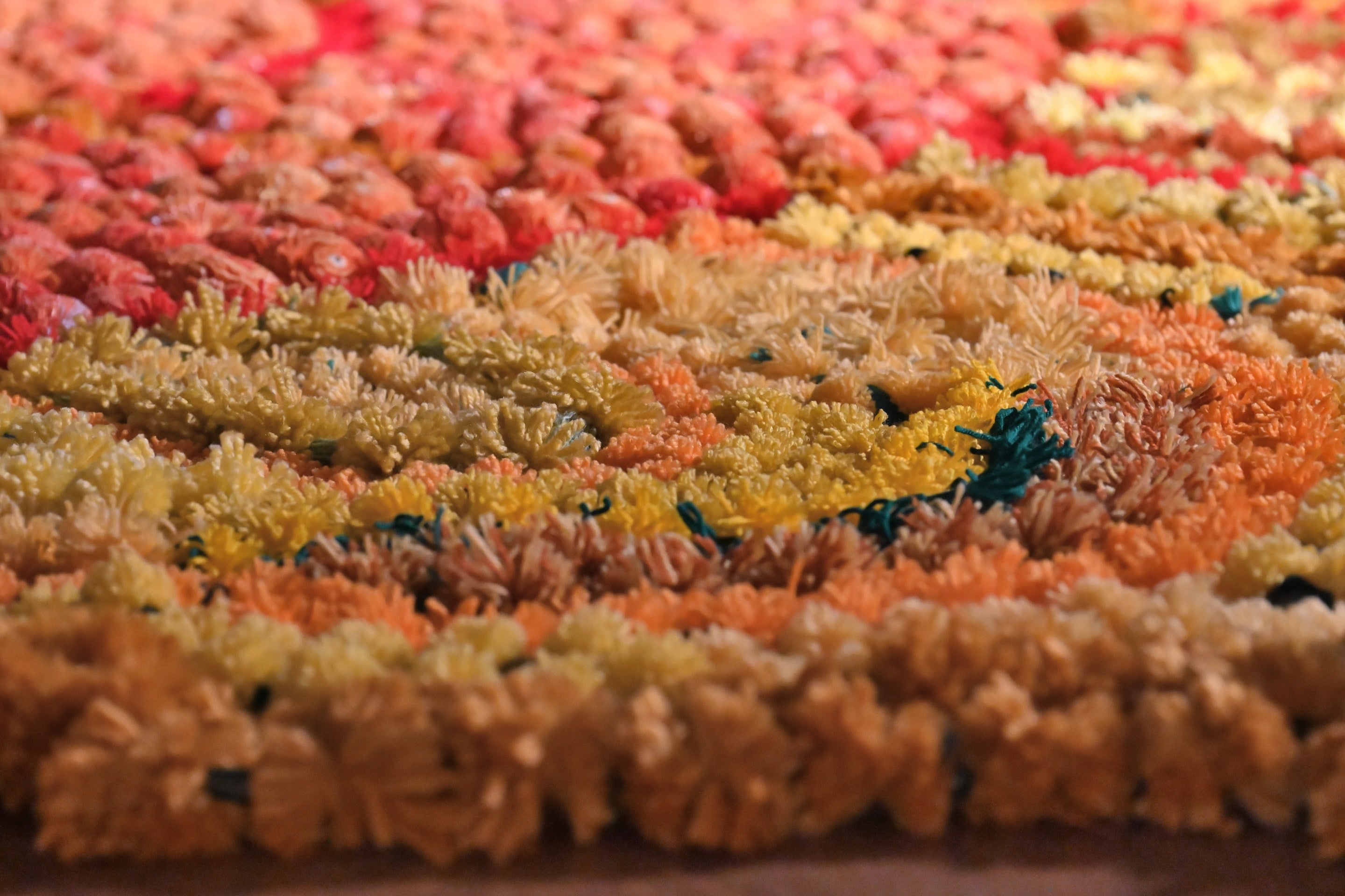 Orange, red and yellow yarn crafted marigold Rangoli display