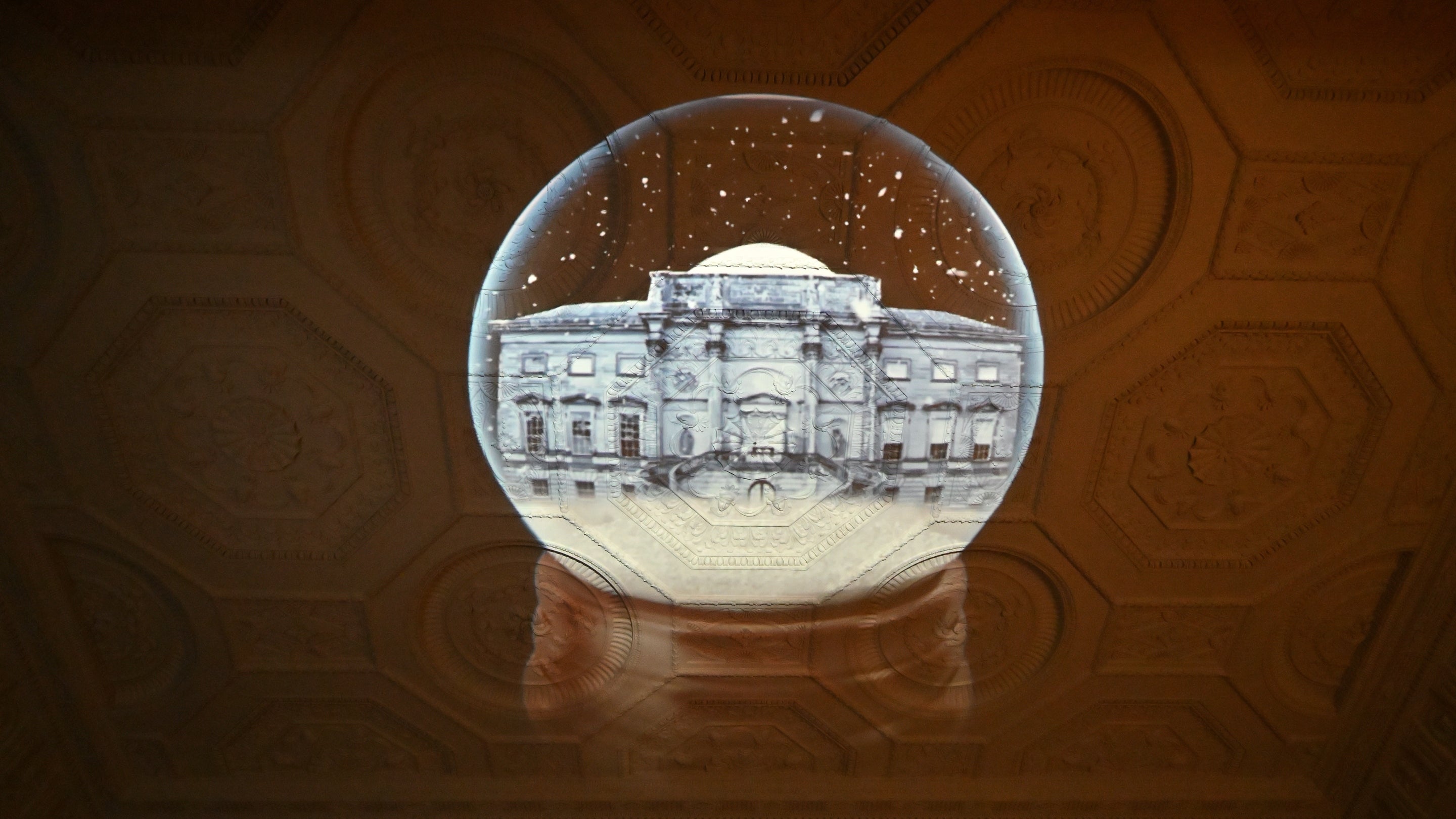A light projection of a grand house shines on an ornate ceiling