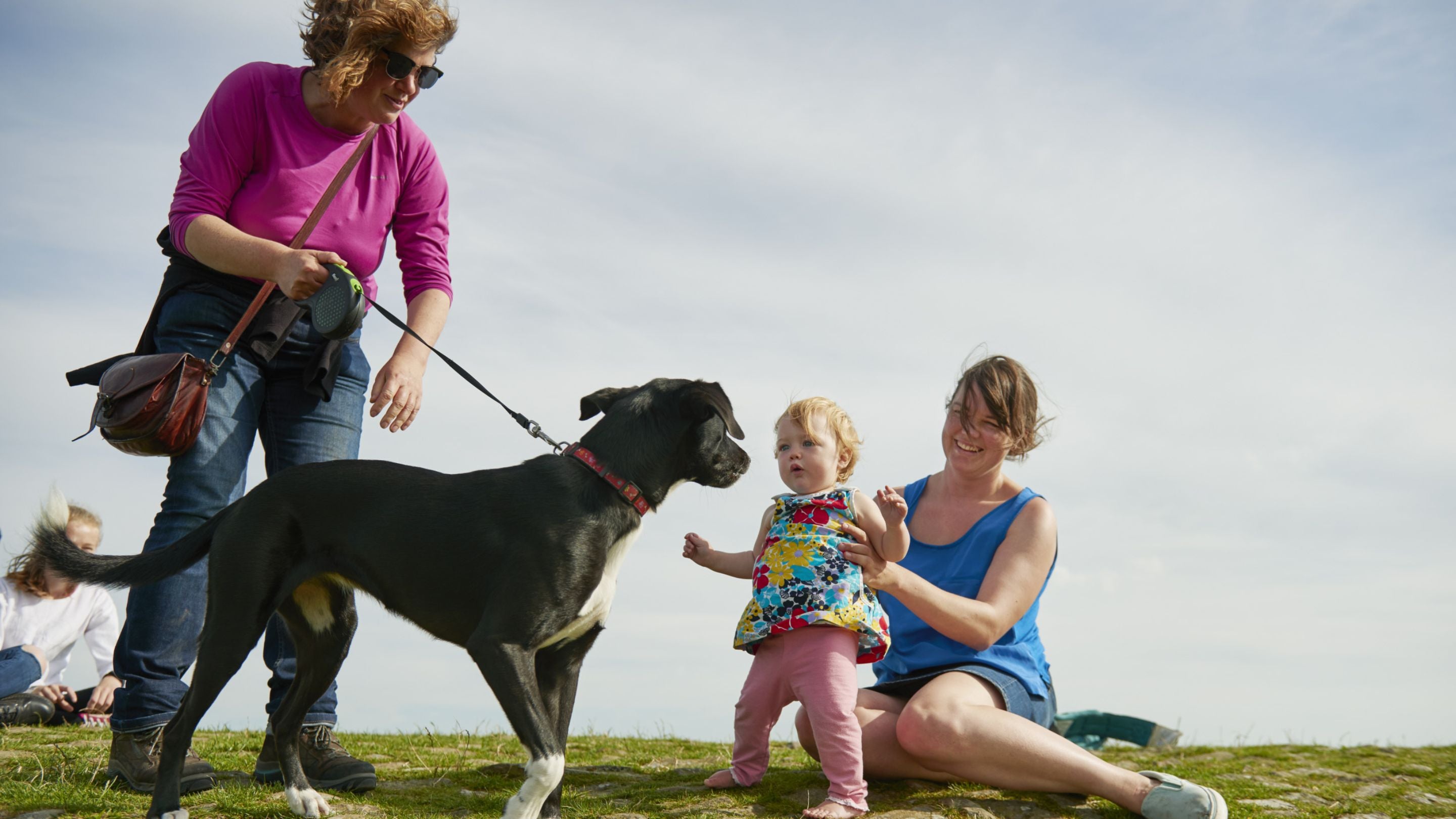 Two women and a small child with a dog on at lead at Mam Tor. High Peak Estate, Peak District, Derbyshire