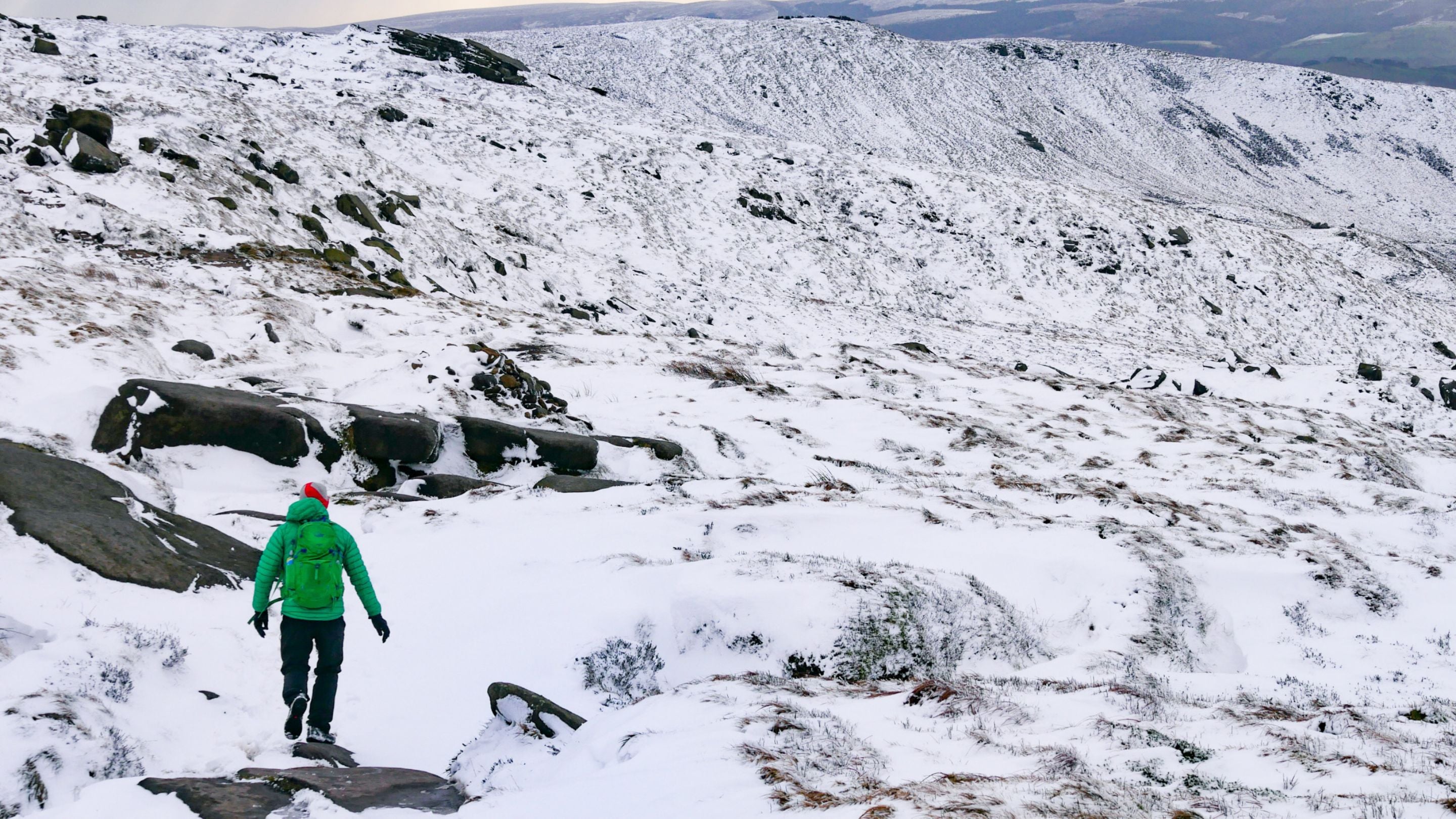 Lone walker on a snowy hillside at Kinder Scout, Derbyshire