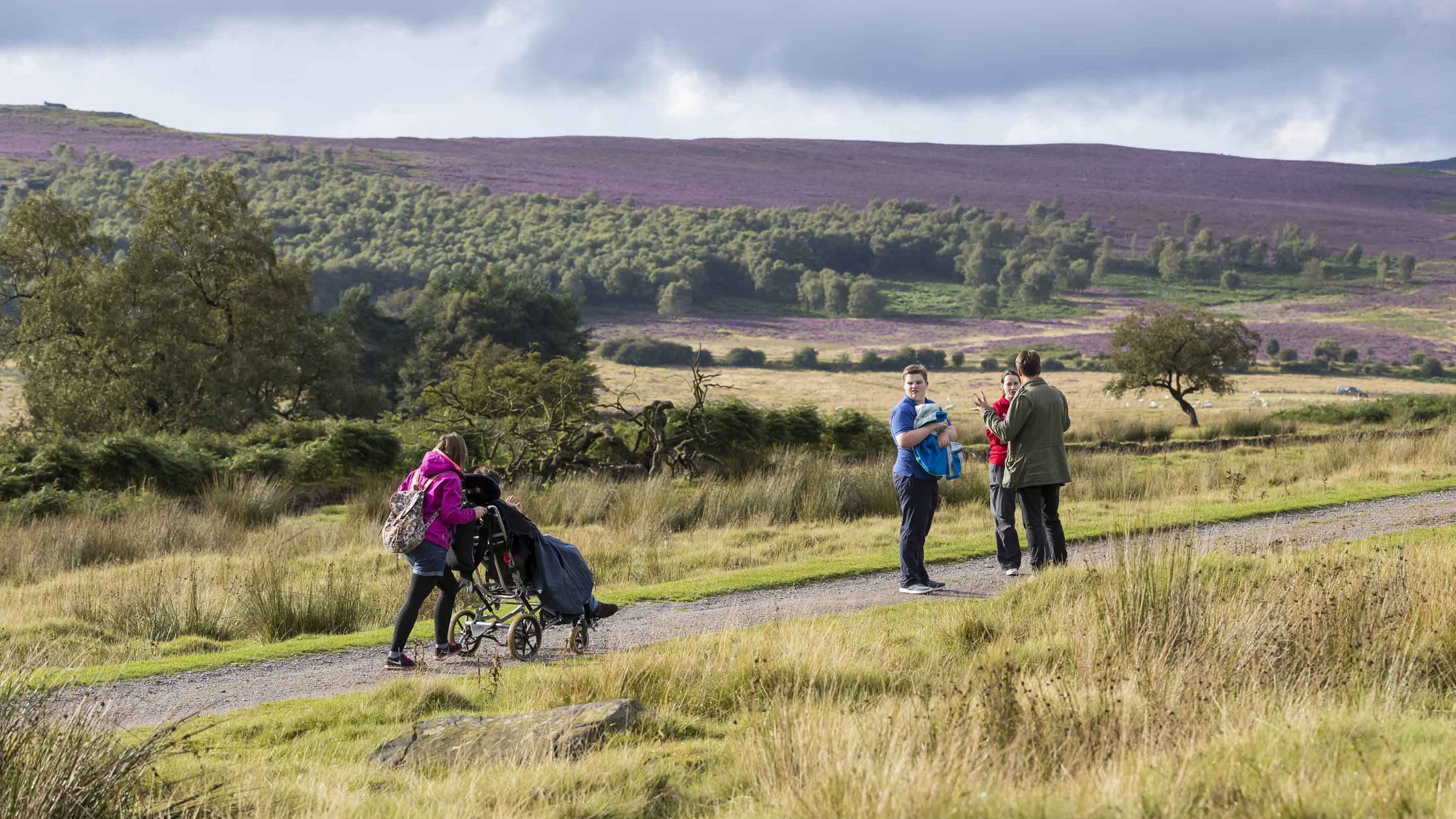 Visitors walking along the accessible path at Longshaw, Burbage and the Eastern Moors, Derbyshire