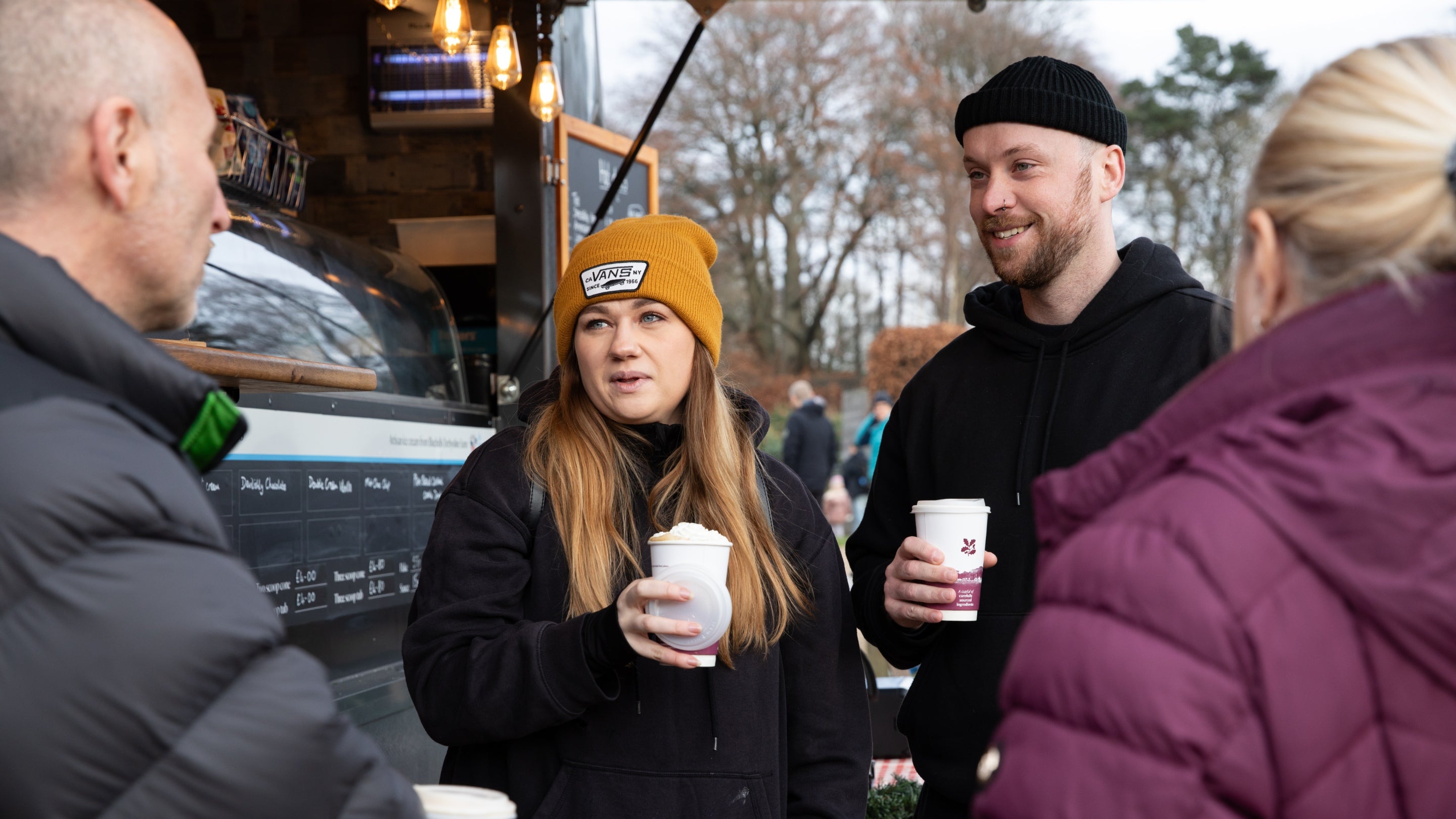 People dressed for winter enjoying a hot drink in front of a refreshment kiosk