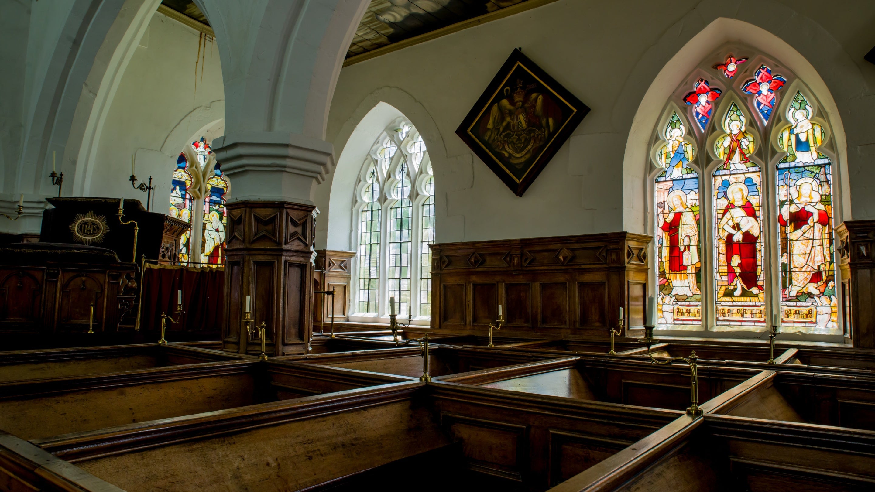 Landscape view of the brown pews in front of colourful stained glass windows