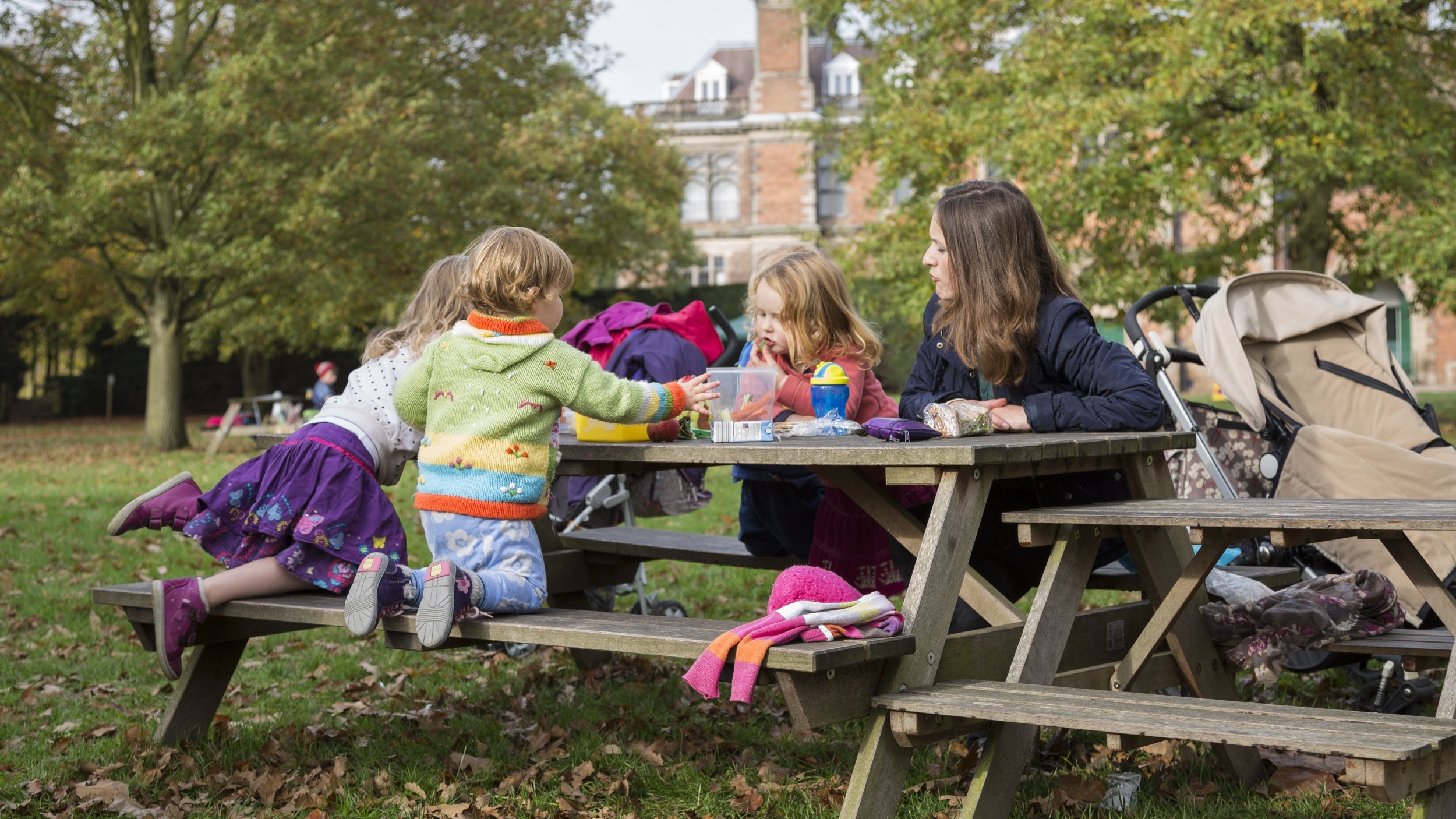Mother with three young children sitting at picnic table with Sudbury Hall in background
