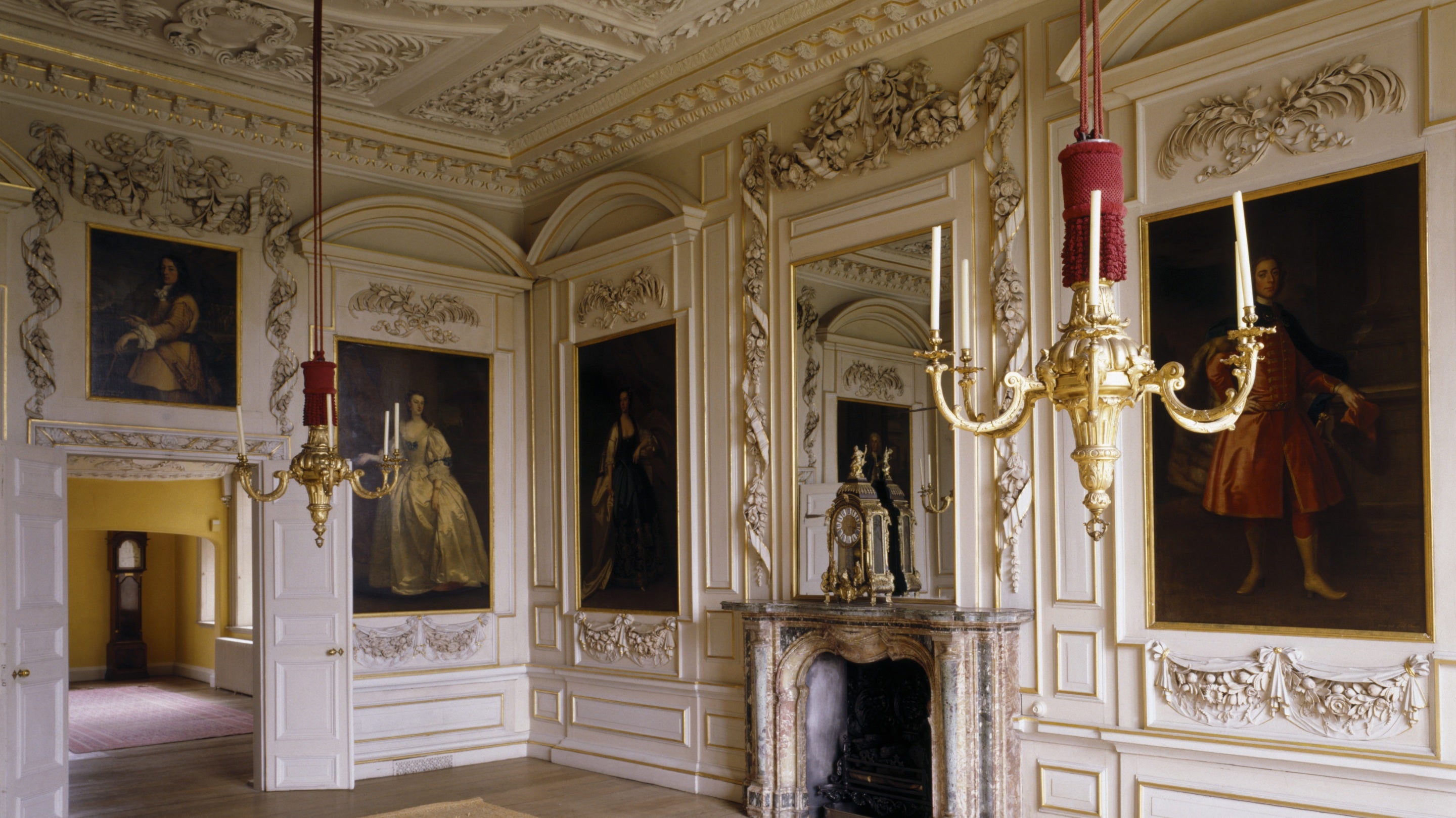 Full length portraits, the fireplace and the elaborate wall carvings by Edward Pierce of 1678 in The Saloon at Sudbury Hall, Derbyshire