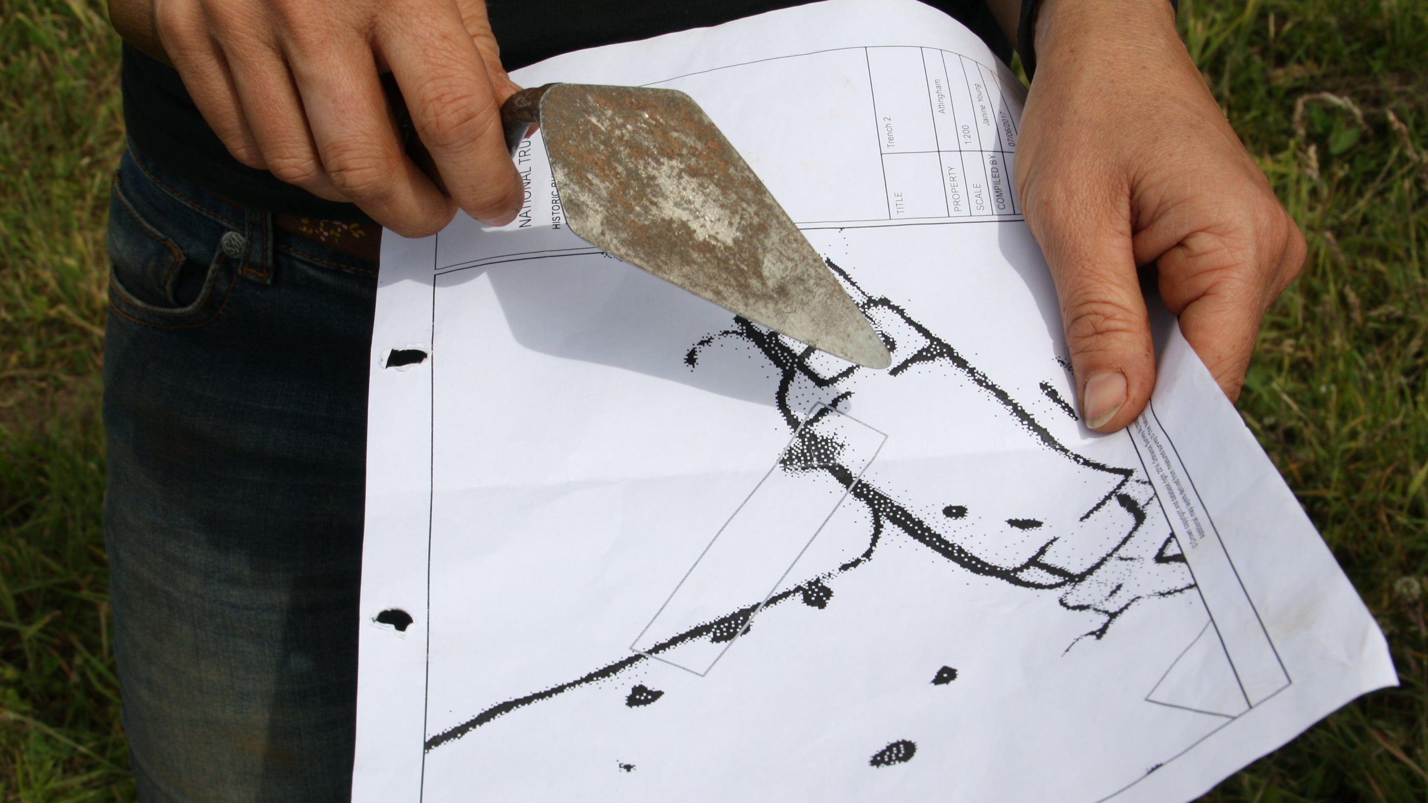 Archaeologist pointing with a trowel to a plan of the Anglo-Saxon palace site, Attingham Park, Shropshire