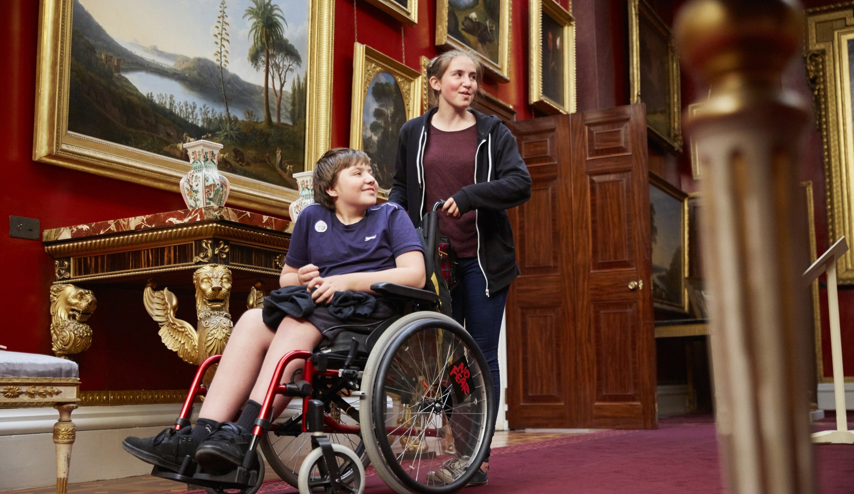 Two visitors exploring the picture gallery at Attingham Park, Shropshire, one is in a wheelchair