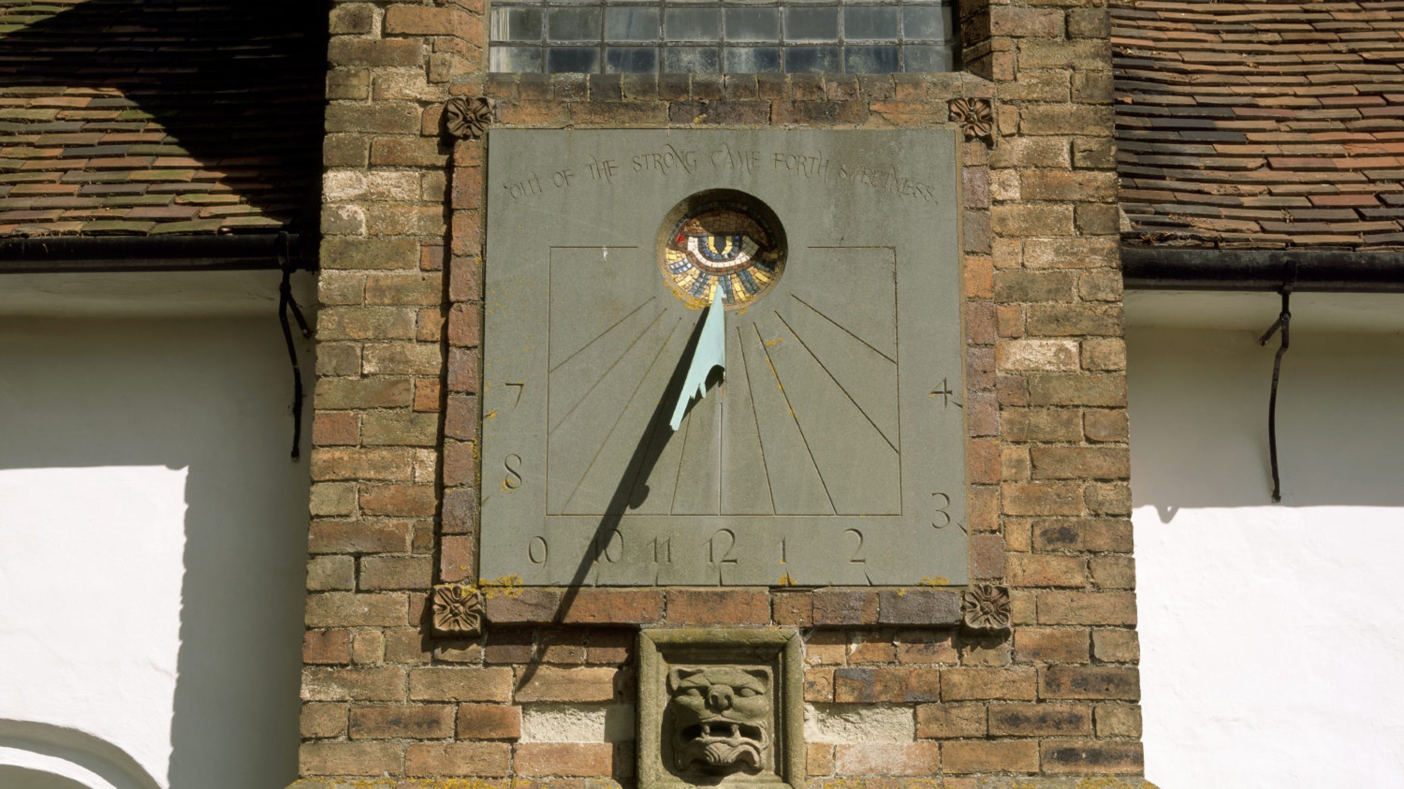 Sundial on the south wall of St Batholomew's Church added at the end of the 19th century. Below is the stone head of a lion whose mouth forms the entrance to a beehive in the gallery of the church.