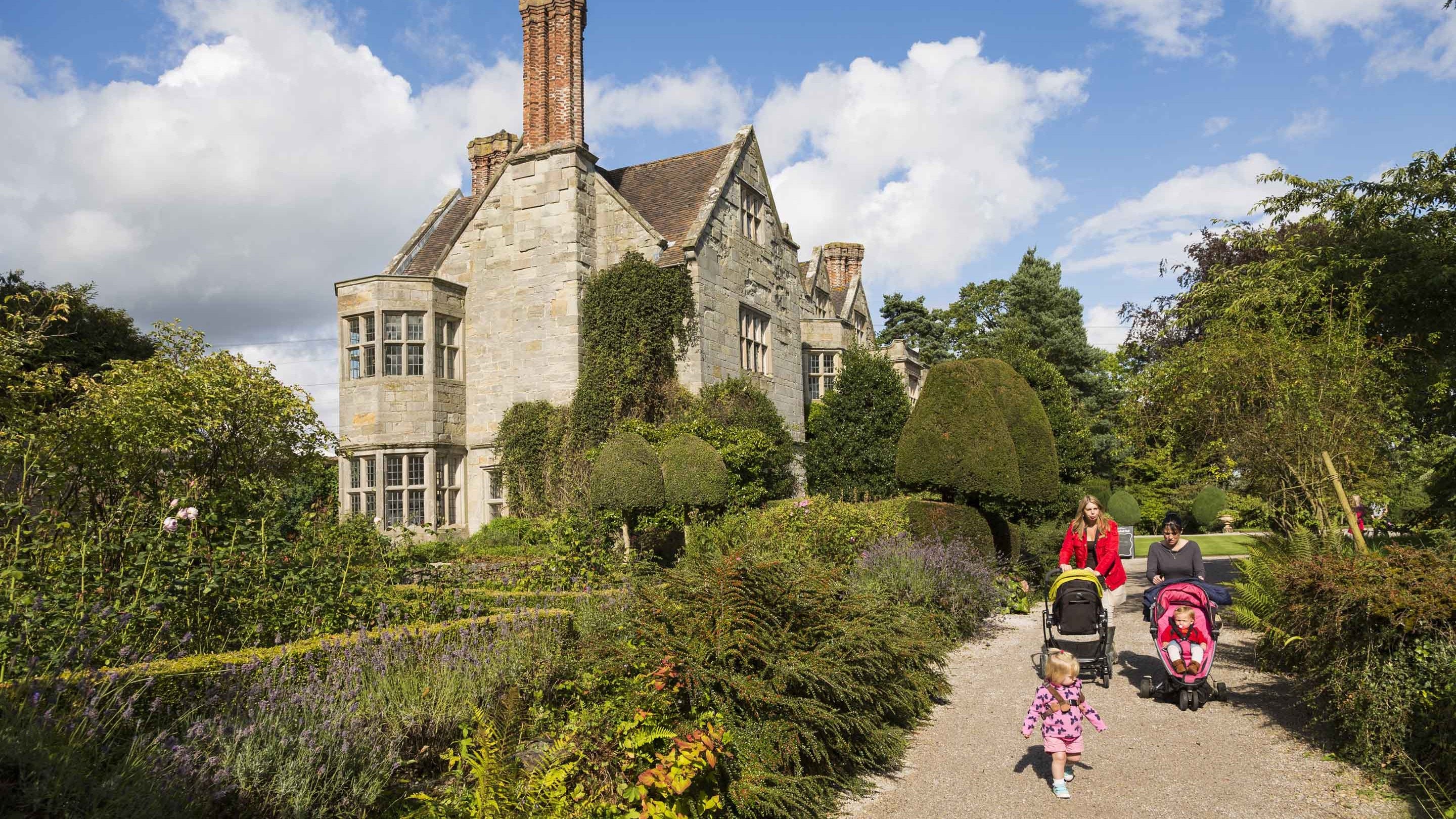 Visitors exploring Benthall Hall, Shropshire. This fine stone house is situated on a plateau above the gorge of the River Severn.