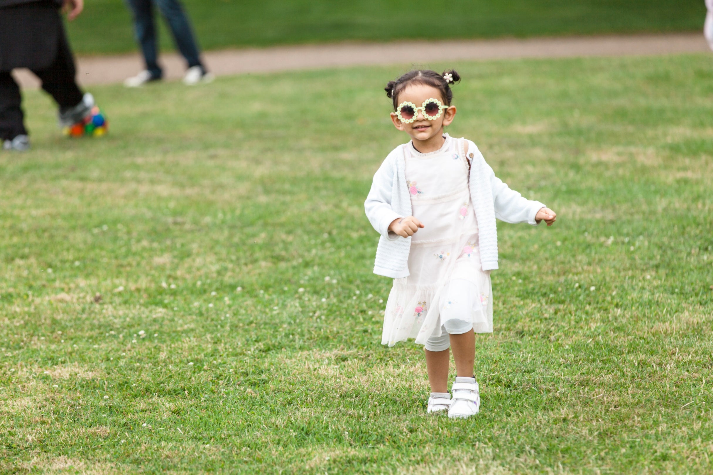 A small child wearing flower shaped sunglasses.