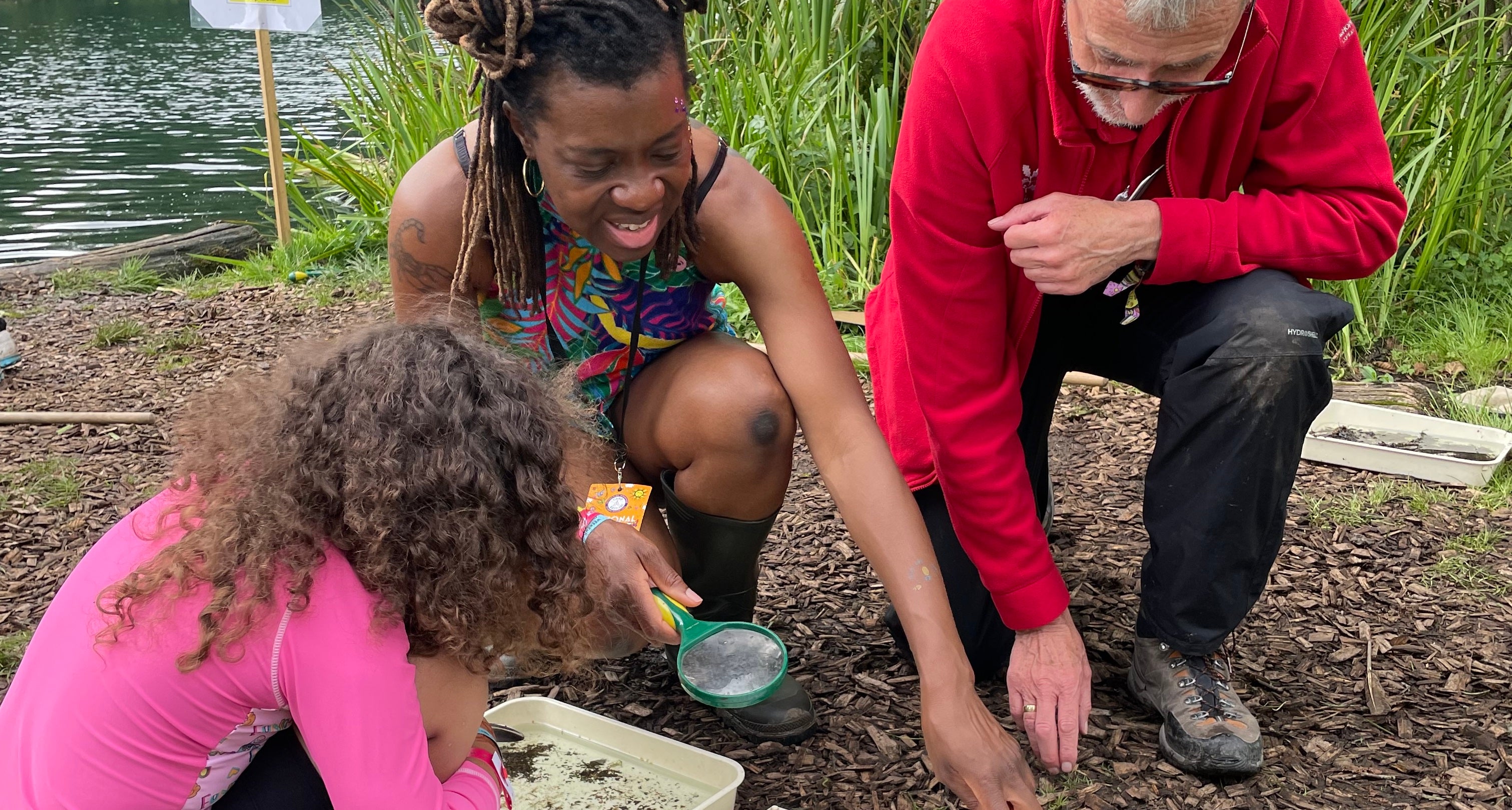 Volunteer points out pond creatures to a mother and daughter