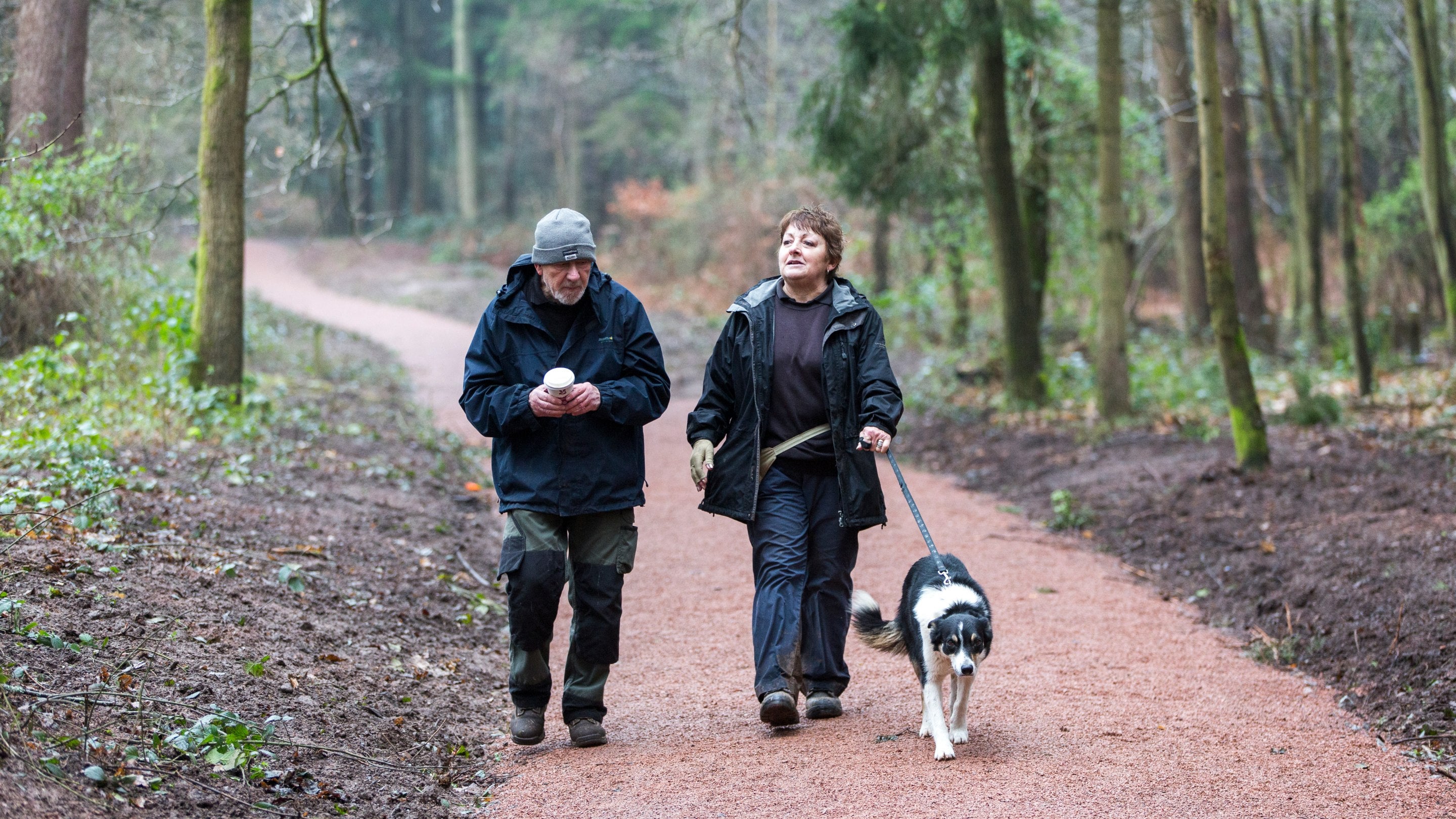 Man and woman walking a dog along new trails at Comer Woods, Dudmaston, Shropshire