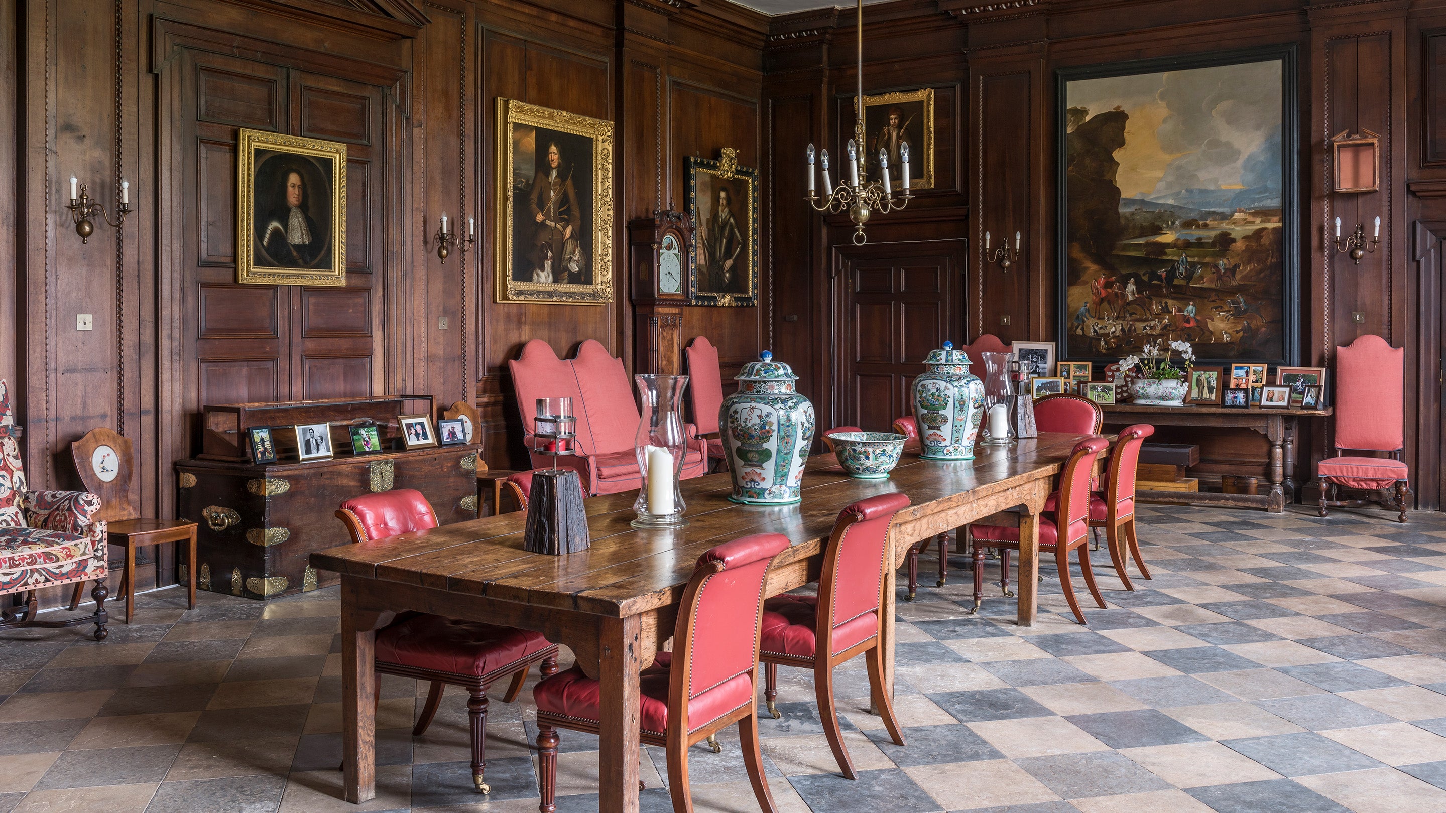 Interior view of the Entrance Hall at Dudmaston, a large refectory table takes up the space with portraits and a landscape picture hung on the wood panelled walls