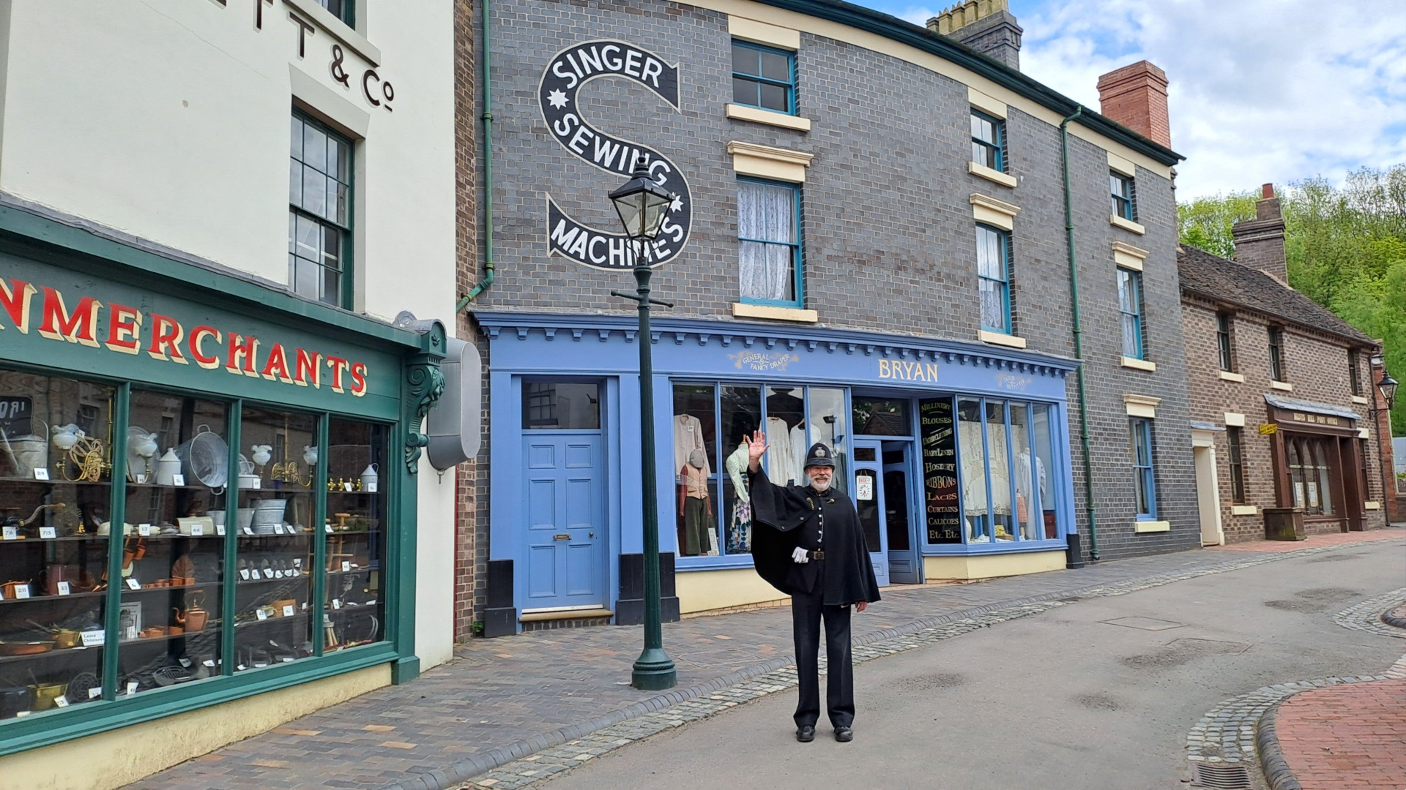 A costumed storyteller dressed as a Victorian policeman waving to welcome visitors to Blists Hill Victorian Town.