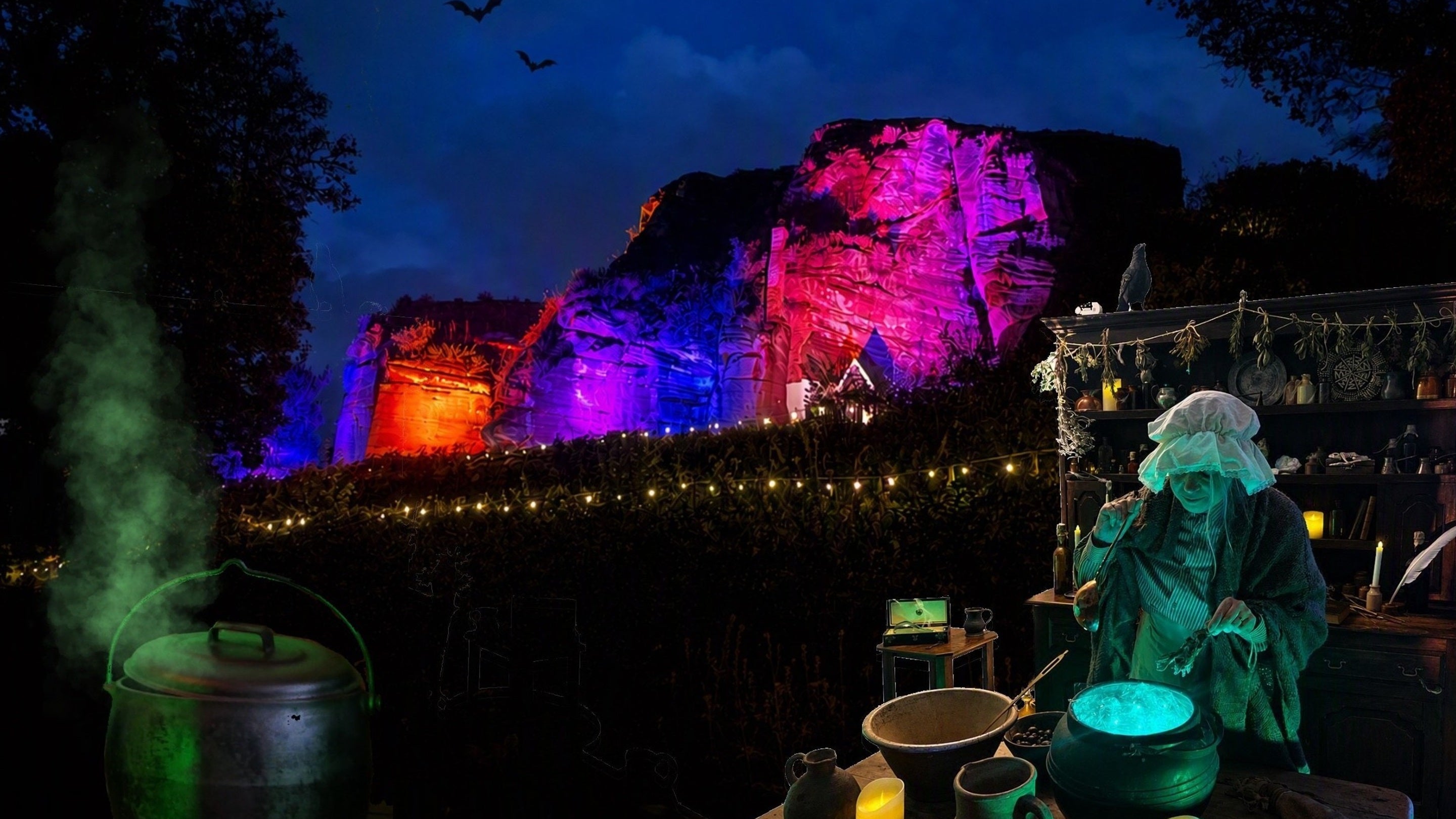 a witch stirs a cauldron in front of illuminated rock houses