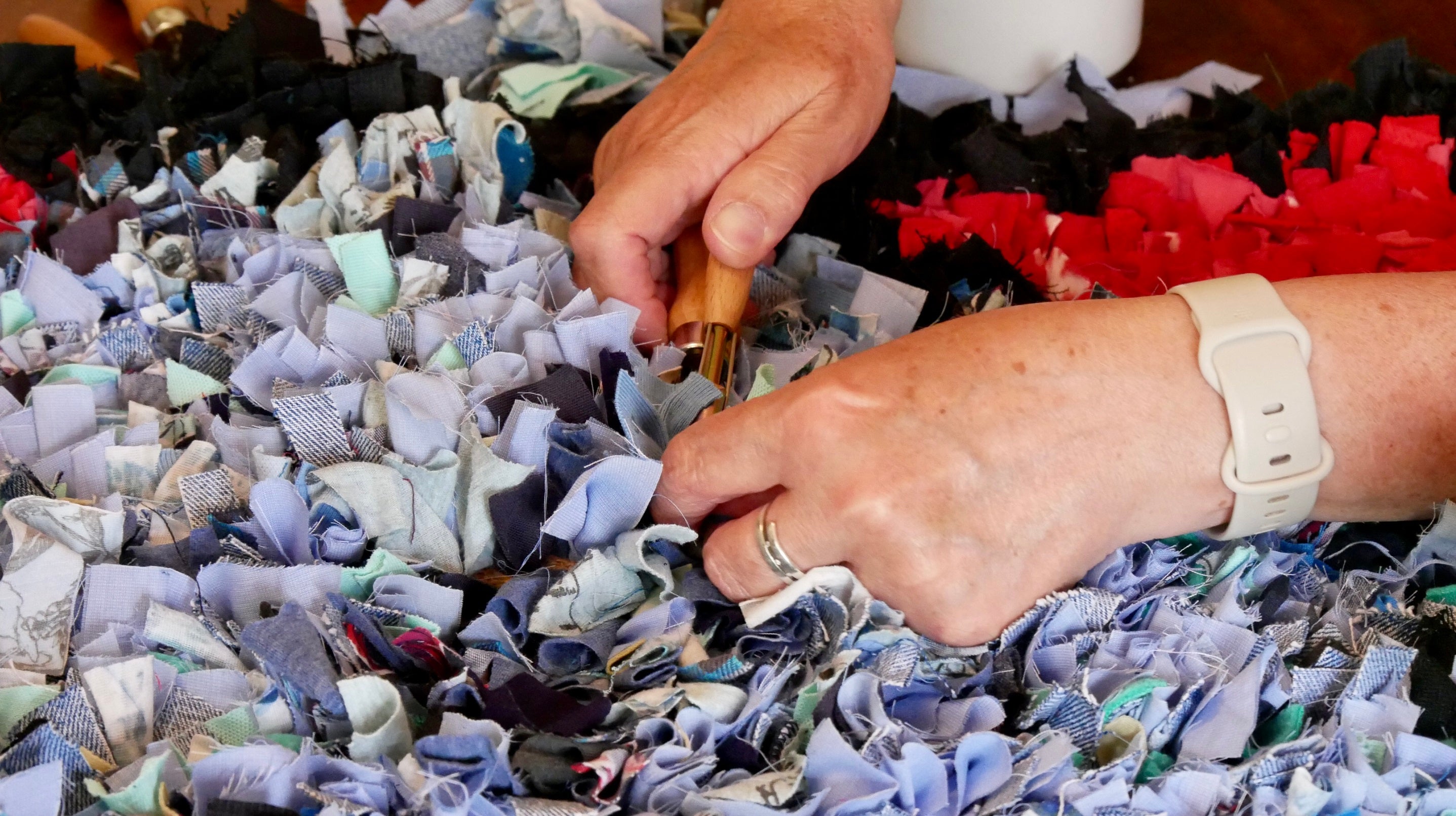 Hands work at making a rag rug