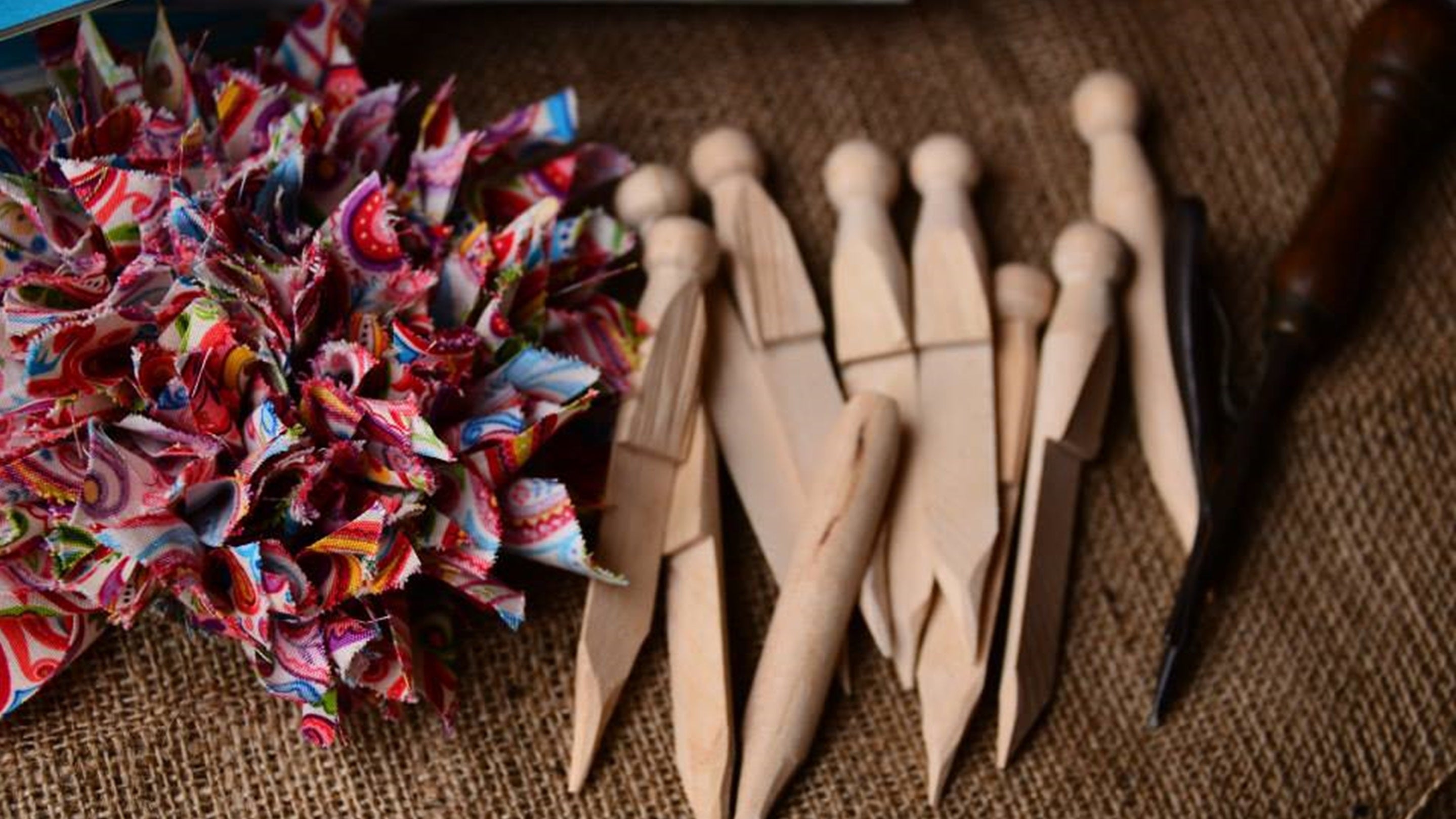 Cut rags poking out of a hessian background, wooden poking tools for rag rugging.