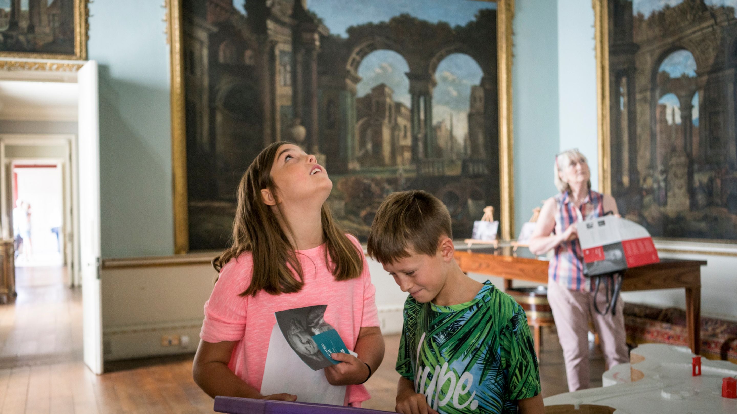 Children using a mirror to view the ceiling in the Dining Room at Shugborough Estate, Staffordshire.