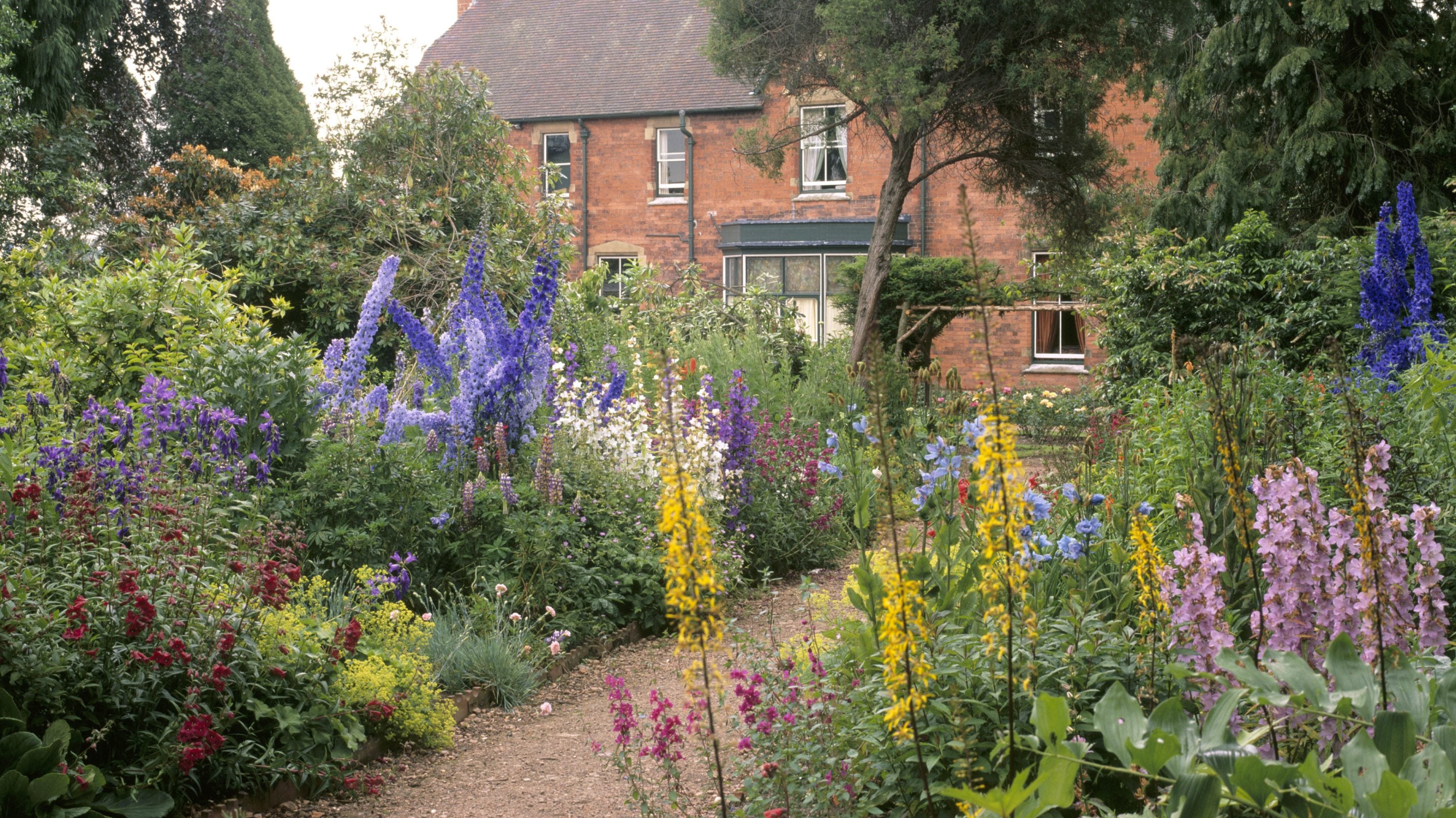A view between an herbaceous border to the East side of Sunnycroft, Shropshire, a red brick late-Victorian house that is one of the few examples remaining of a gentleman's suburban villa