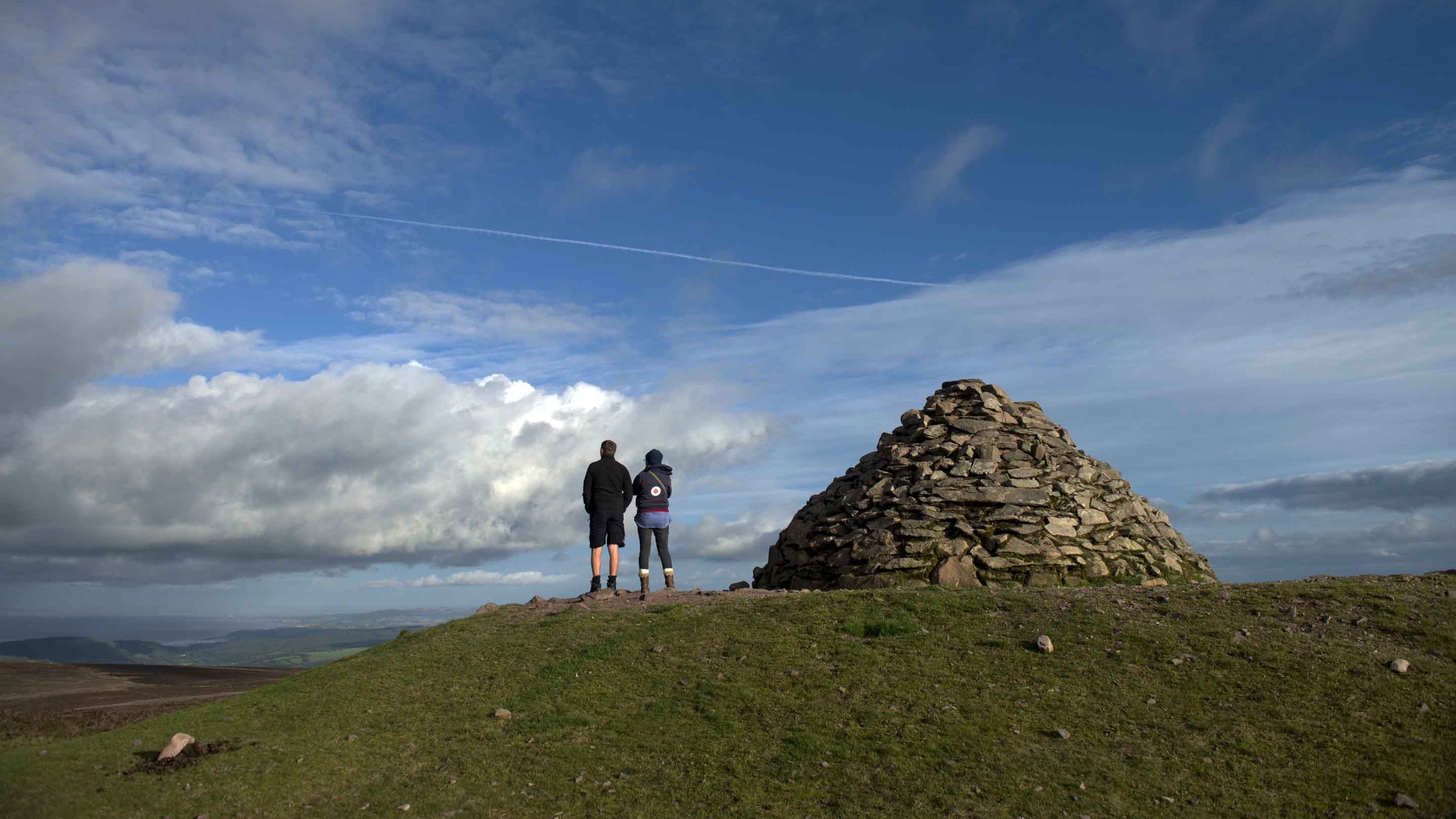 Two walkers standing next to a rock formation at Dunkery Beacon on the Holnicote Estate