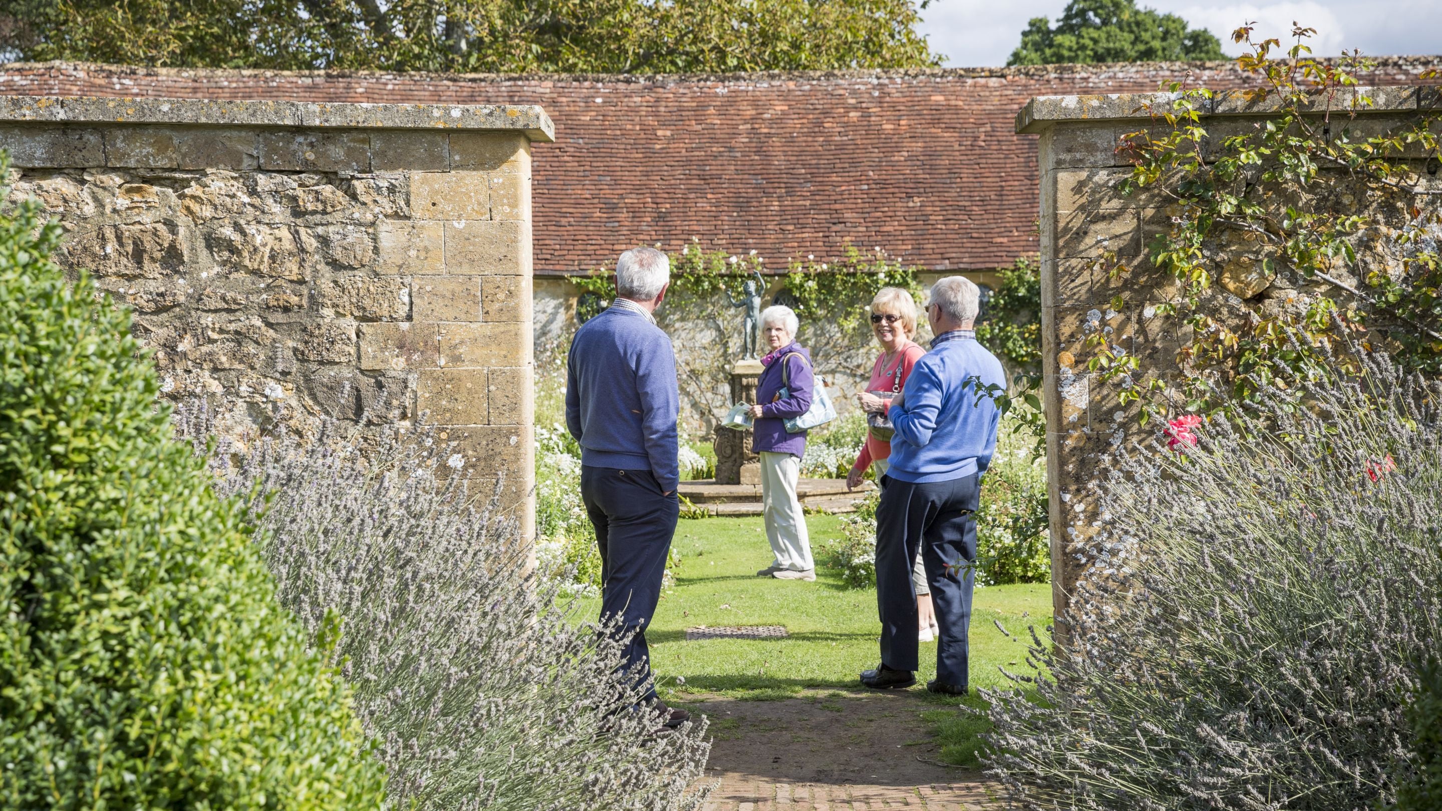 A small group of older visitors exploring the White Garden at Barrington Court, Somerset