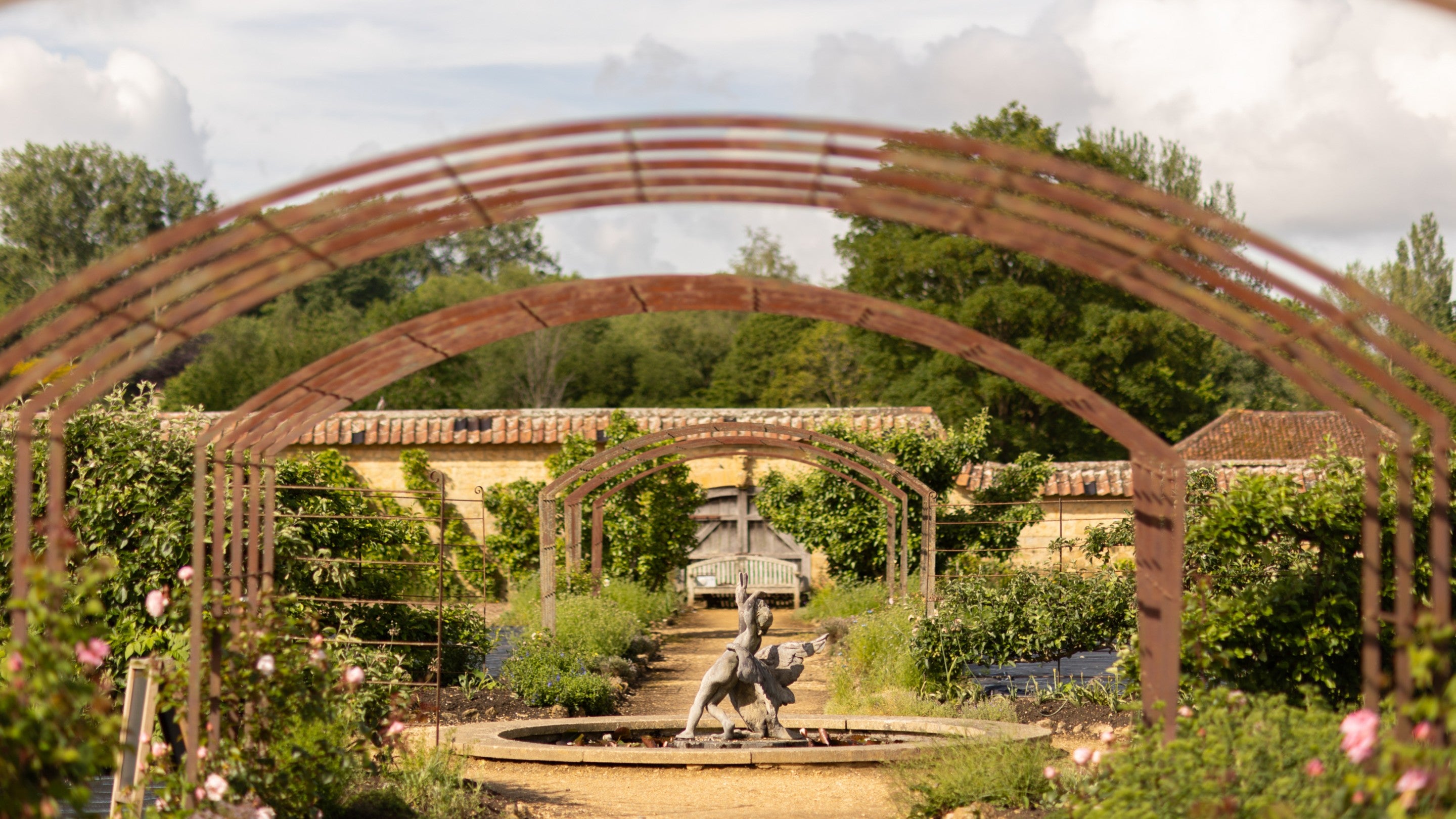 Fountain statue of a boy with a swan  on the lily pond in the Kitchen Garden at Barrington Court, Somerset
