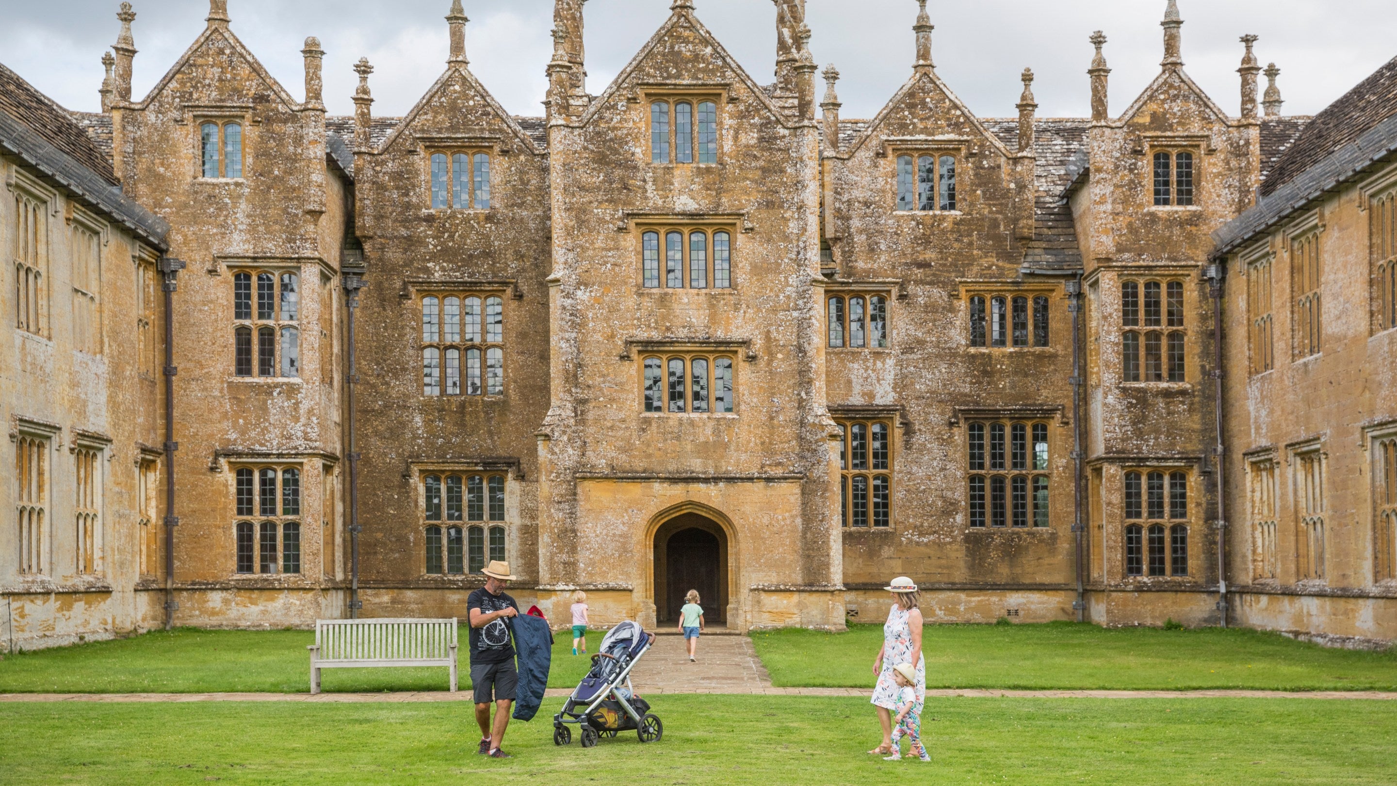 A family explore the grounds immediately in front of the house at Barrington Court, Somerset in summer
