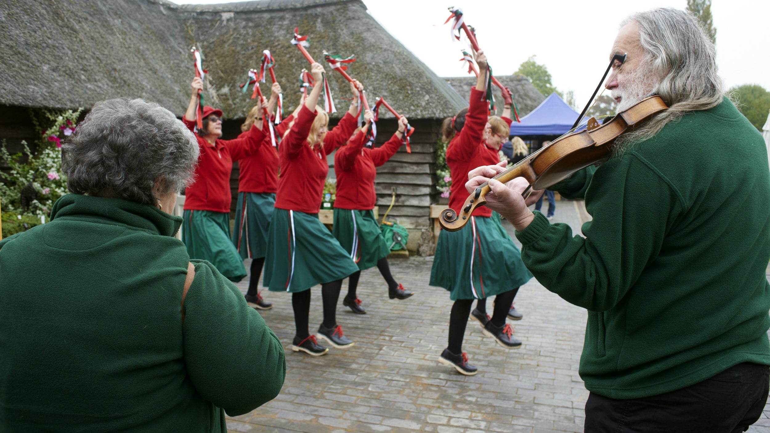 Musicians playing in courtyard to accompany troupe of dancers with bells and sticks