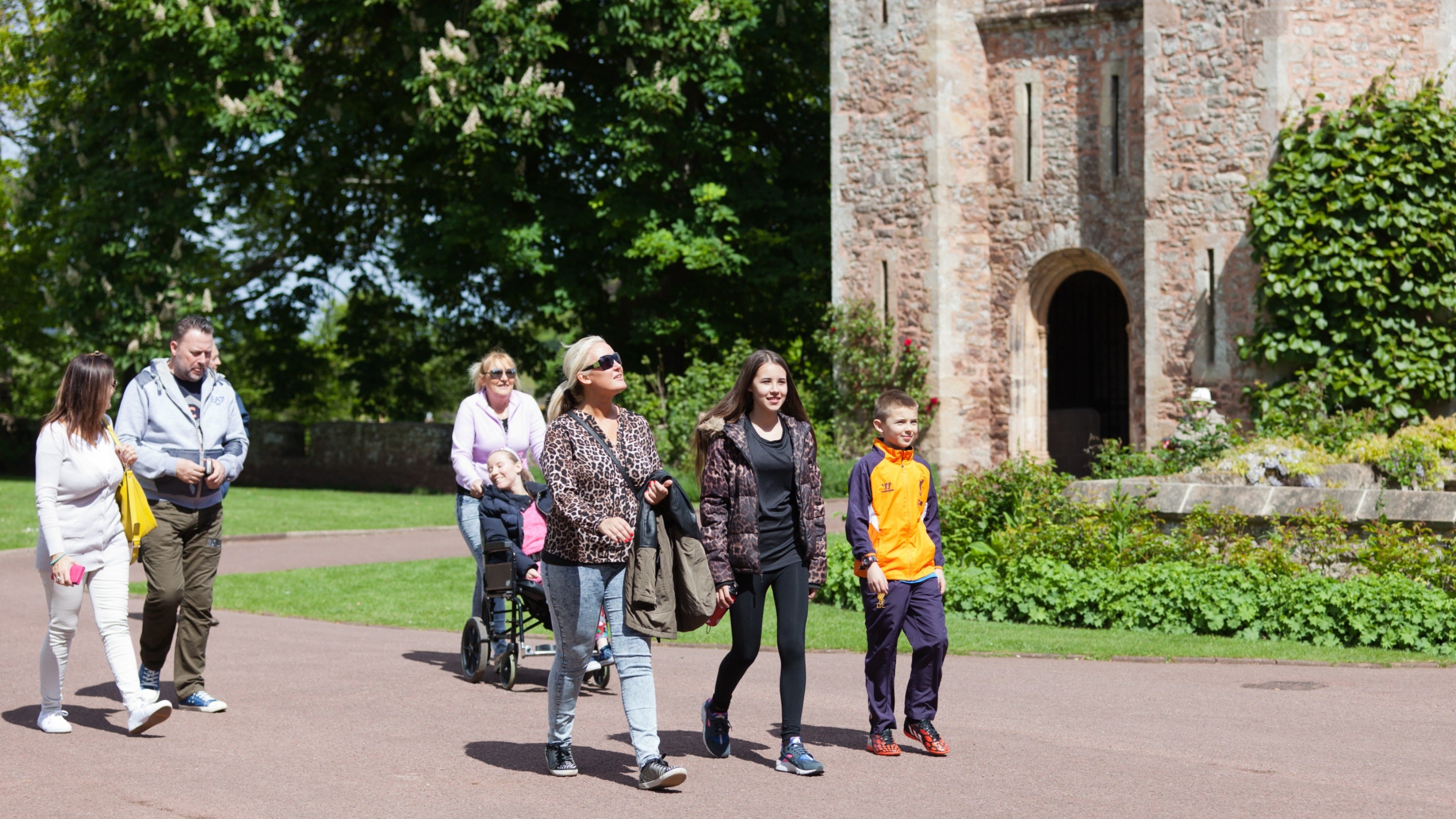 A group of visitors walking past an archway entrance at Dunster Castle