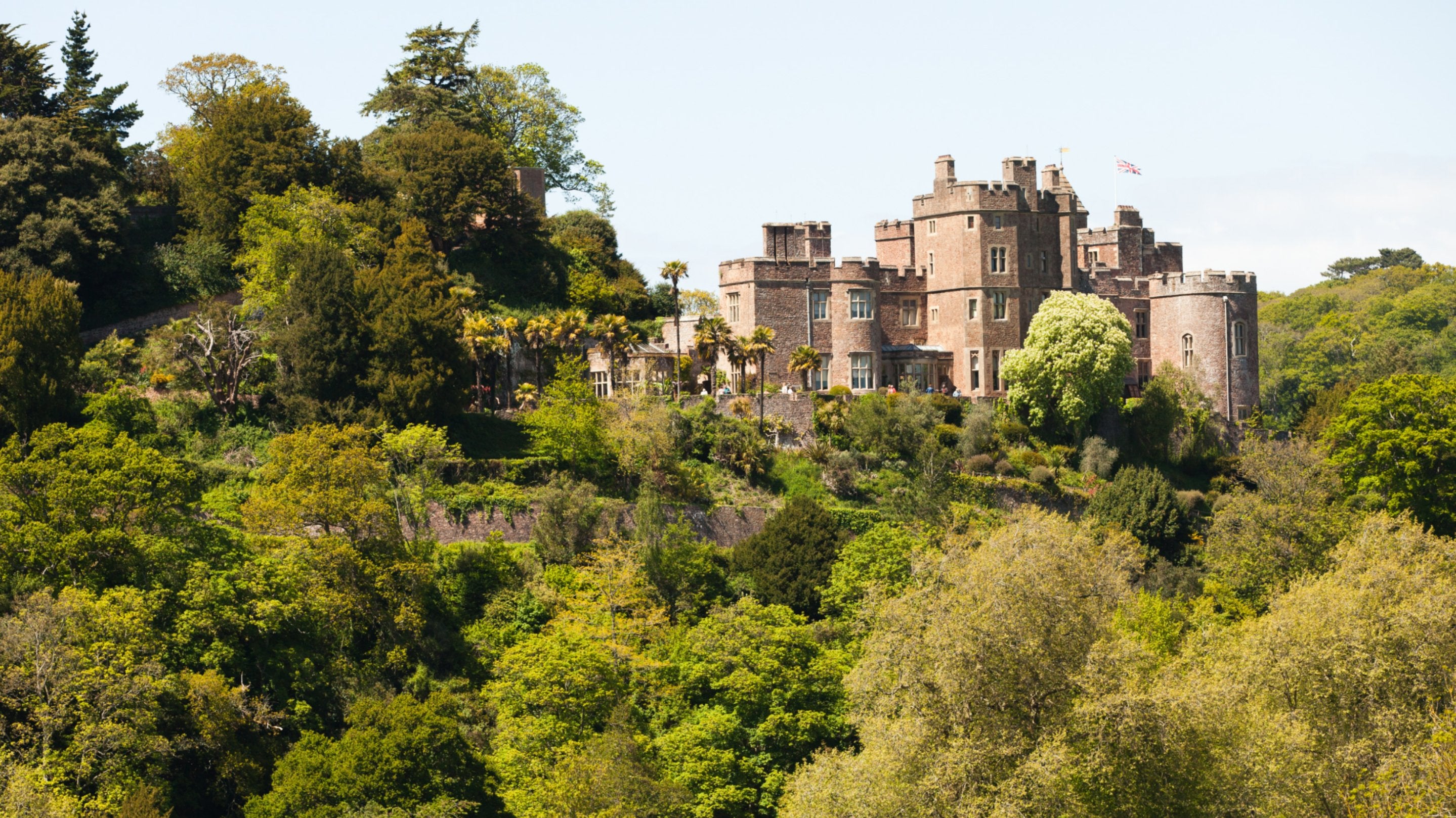 A red stone castle on a high, wooded hill
