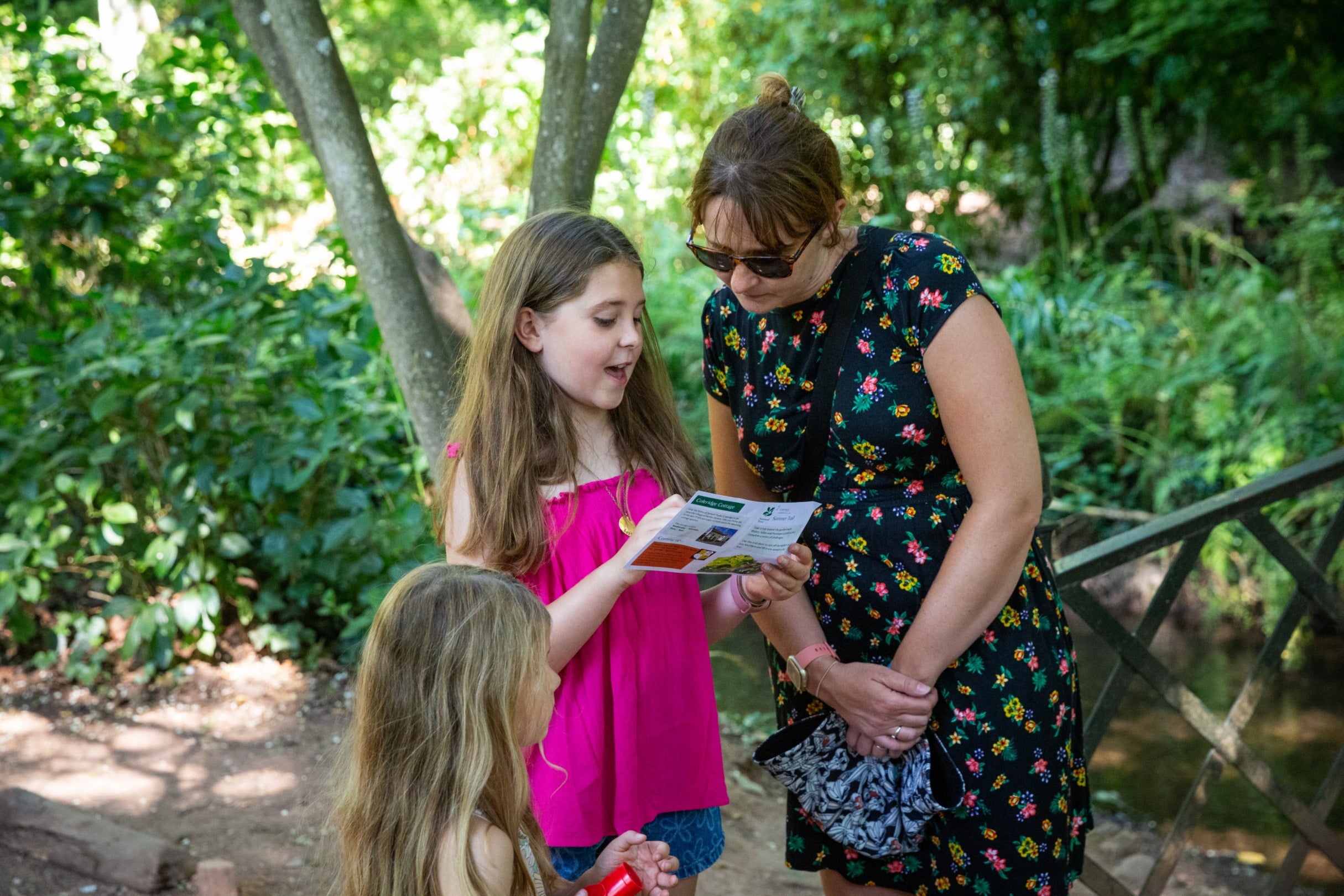 A woman with two children look at a trail sheet in the gardens at Dunster Castle