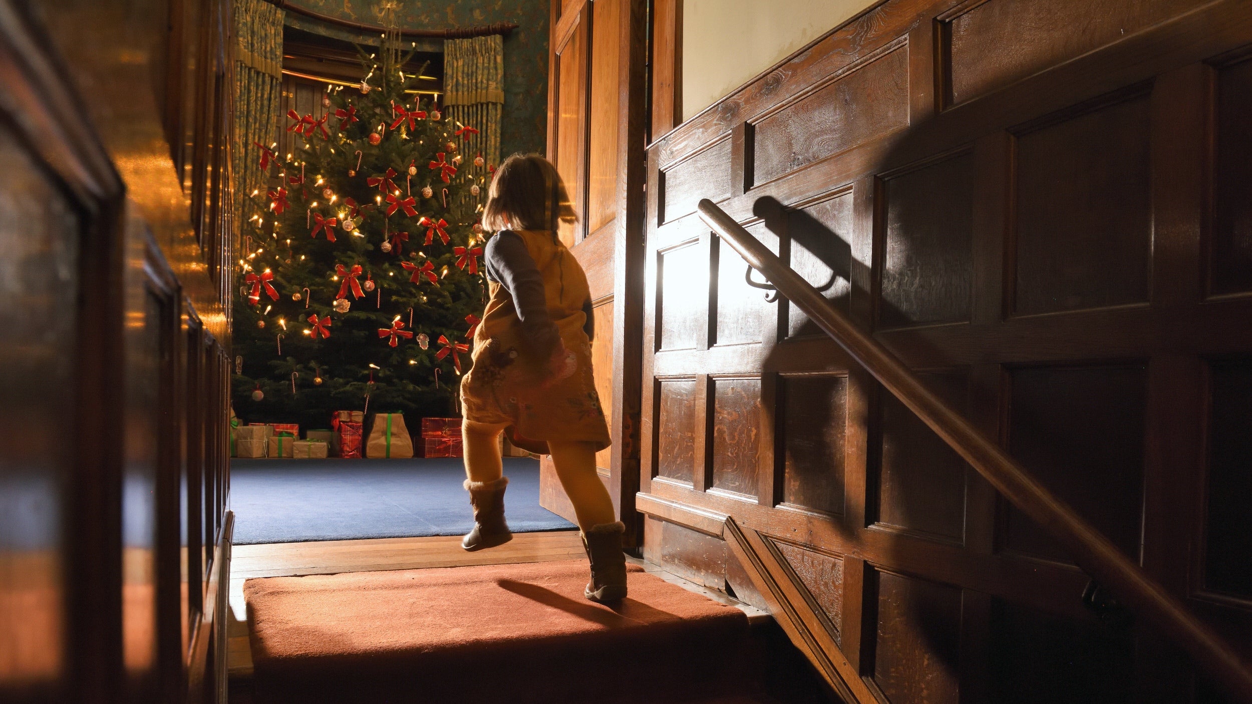 A child running towards a Christmas tree at Dunster Castle in Somerset