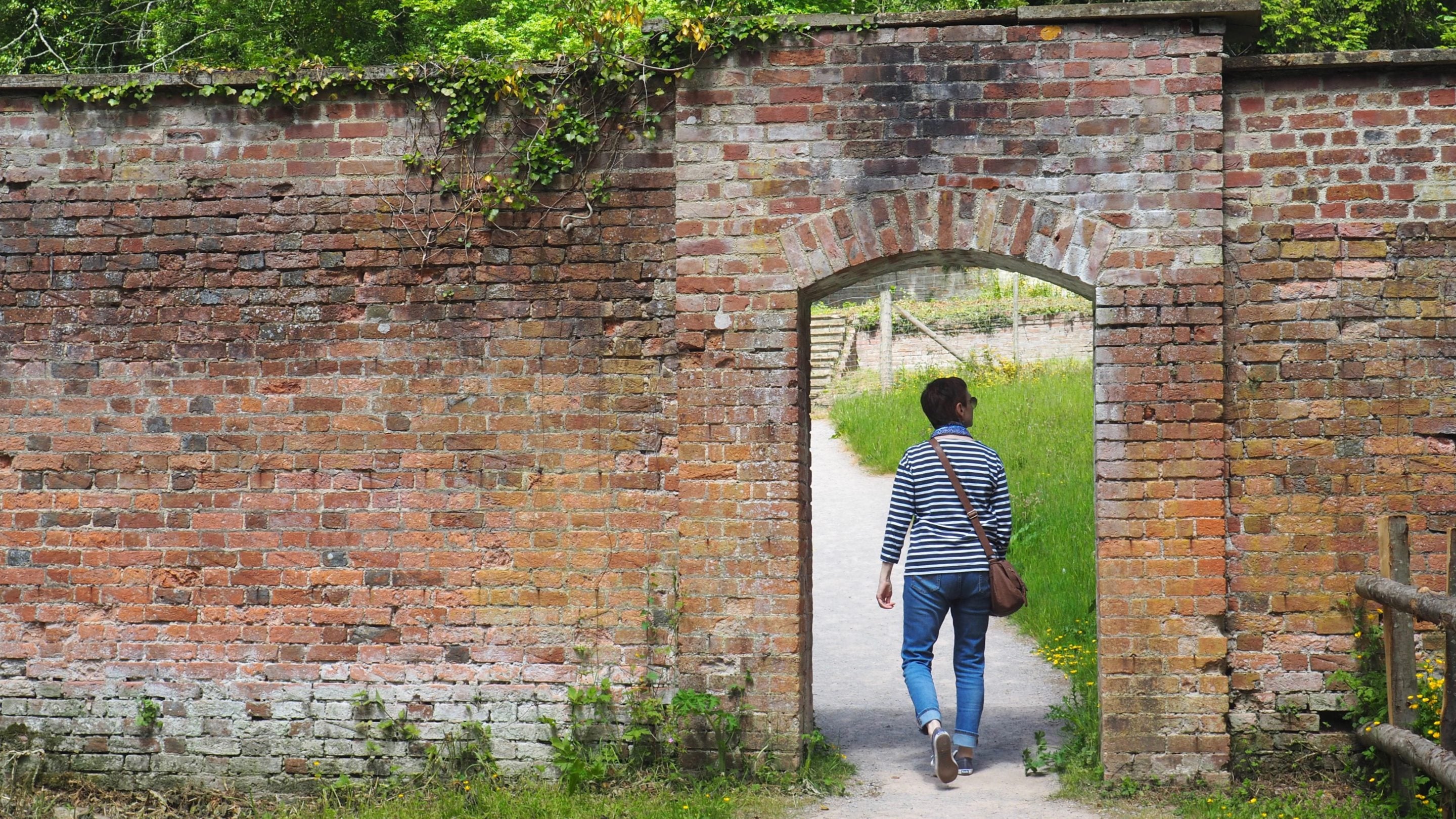 A visitor walking through the entrance into the Walled Garden at Fyne Court, Somerset