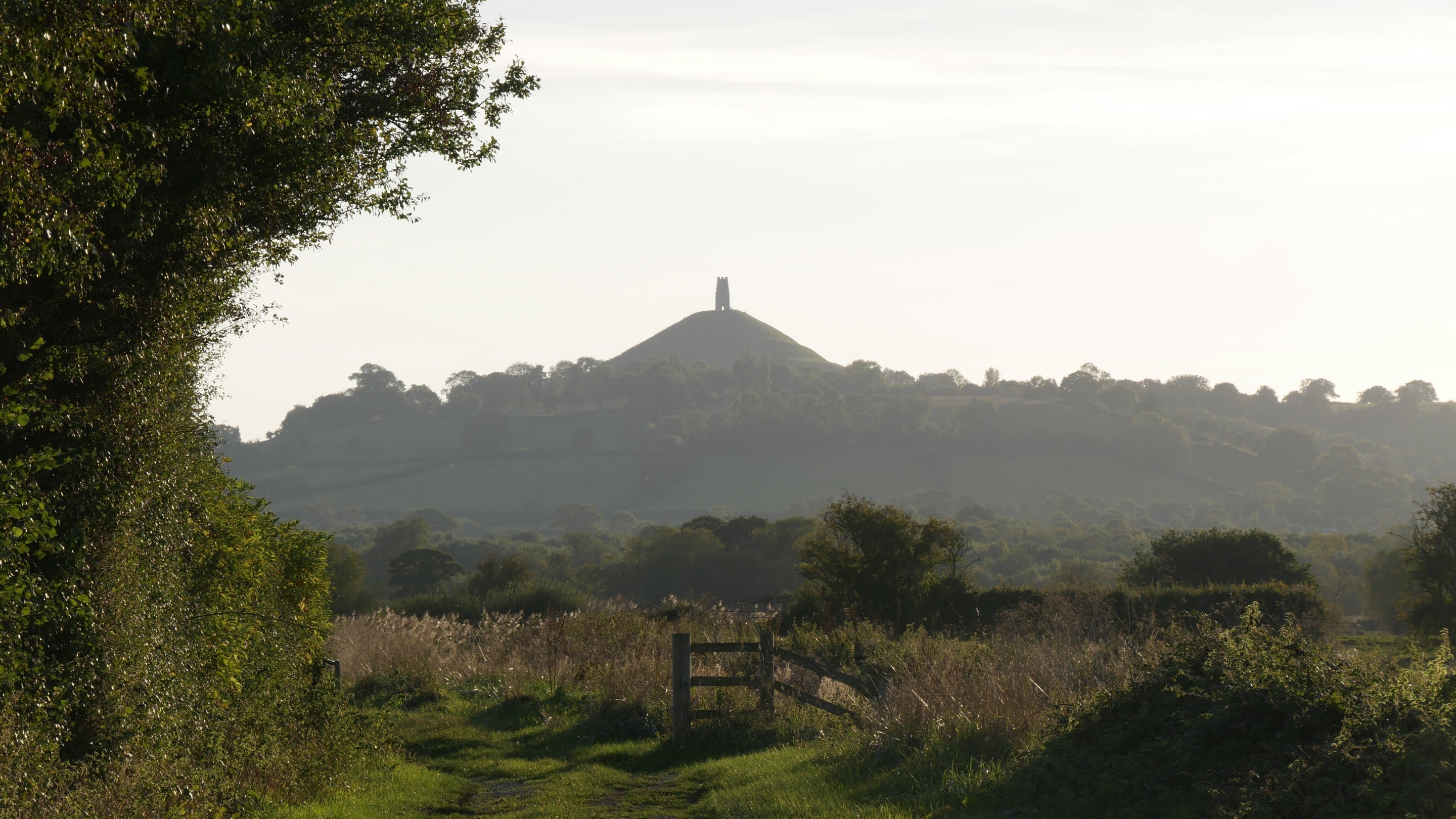 Evening sun setting over the countryside of Glastonbury Tor, Somerset with the tower in the distance