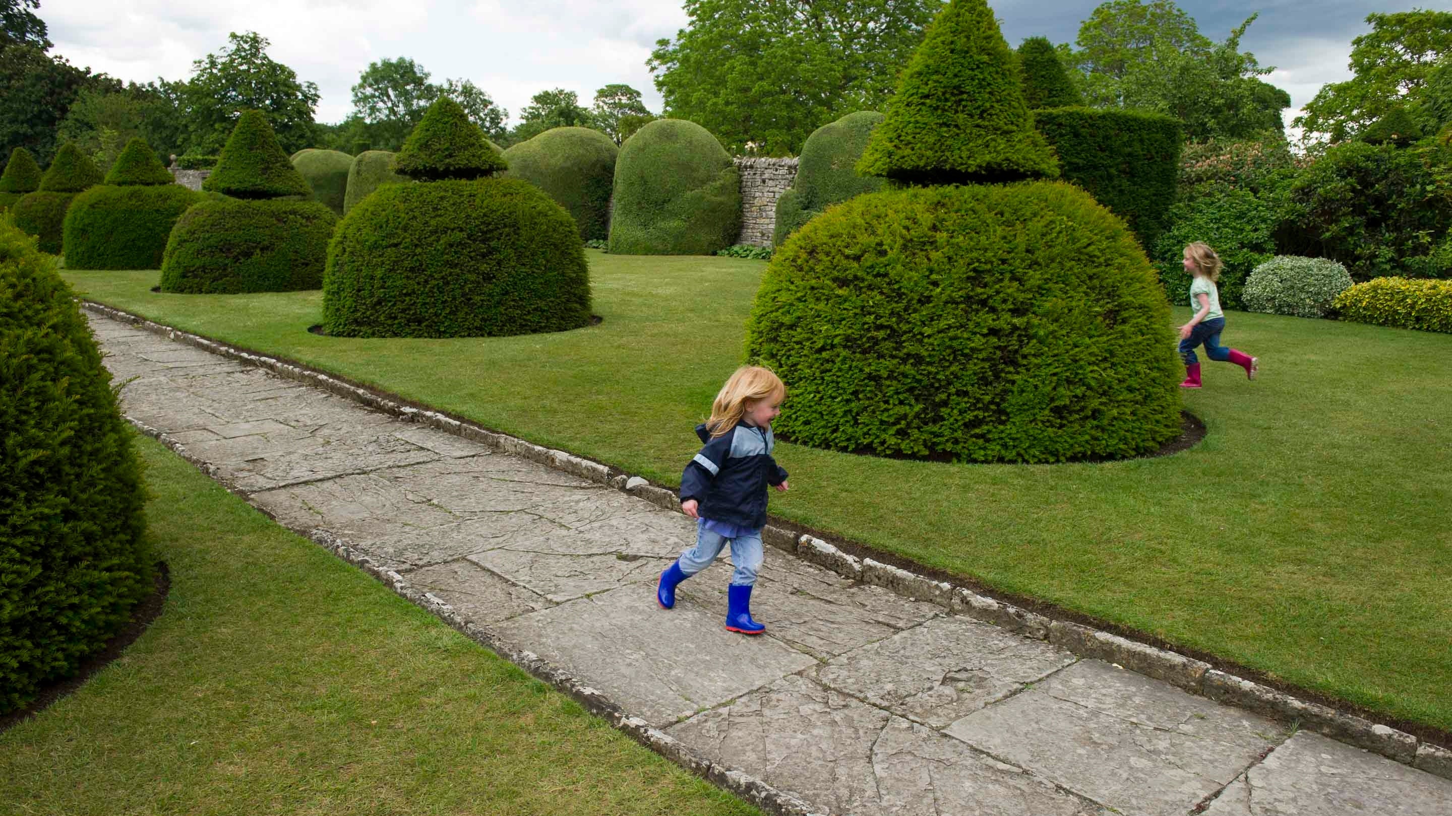 Two children run around in the garden at Lytes Cary Manor