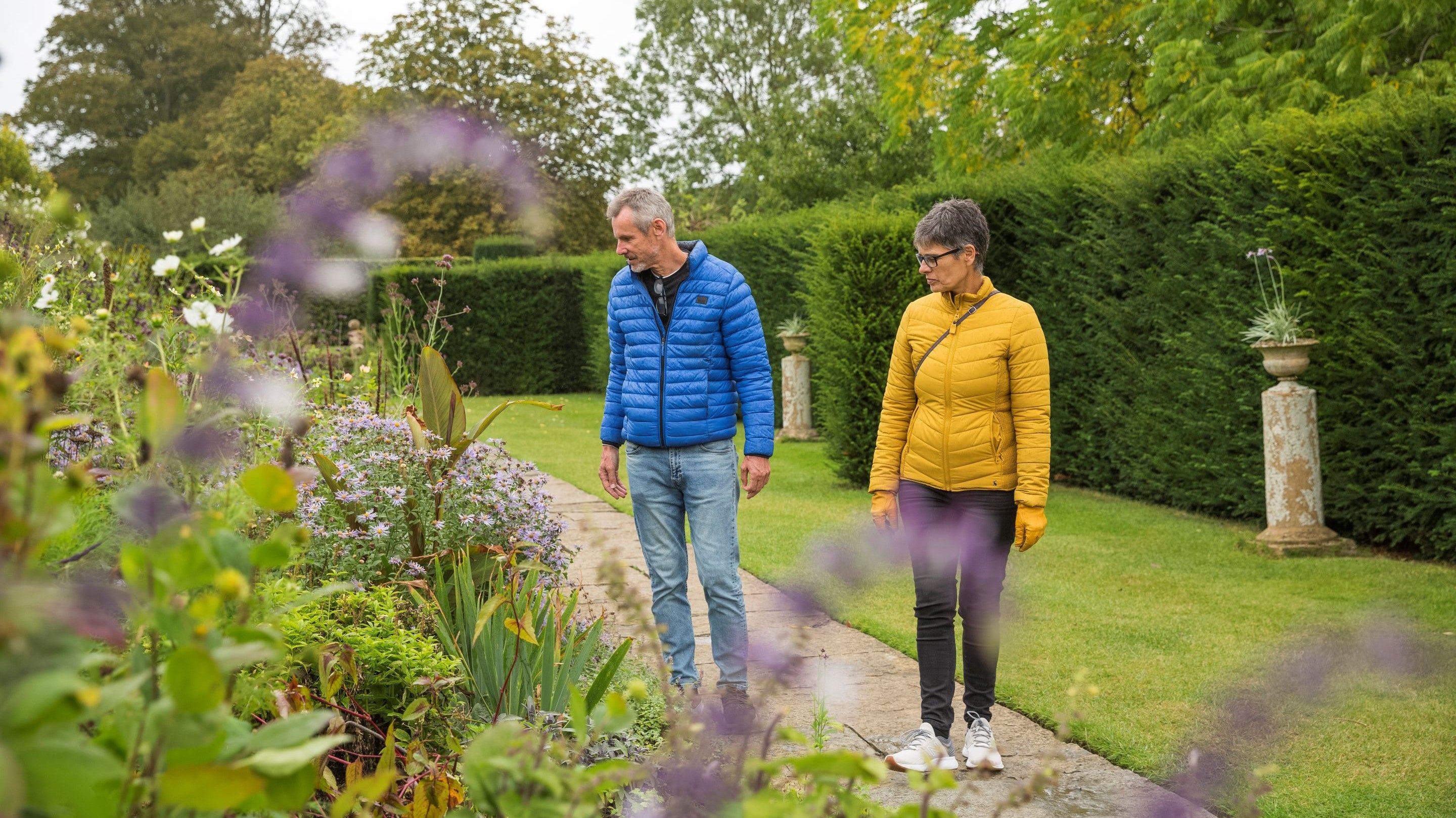 Two visitors looking at a long border in the garden at Lytes Cary Manor