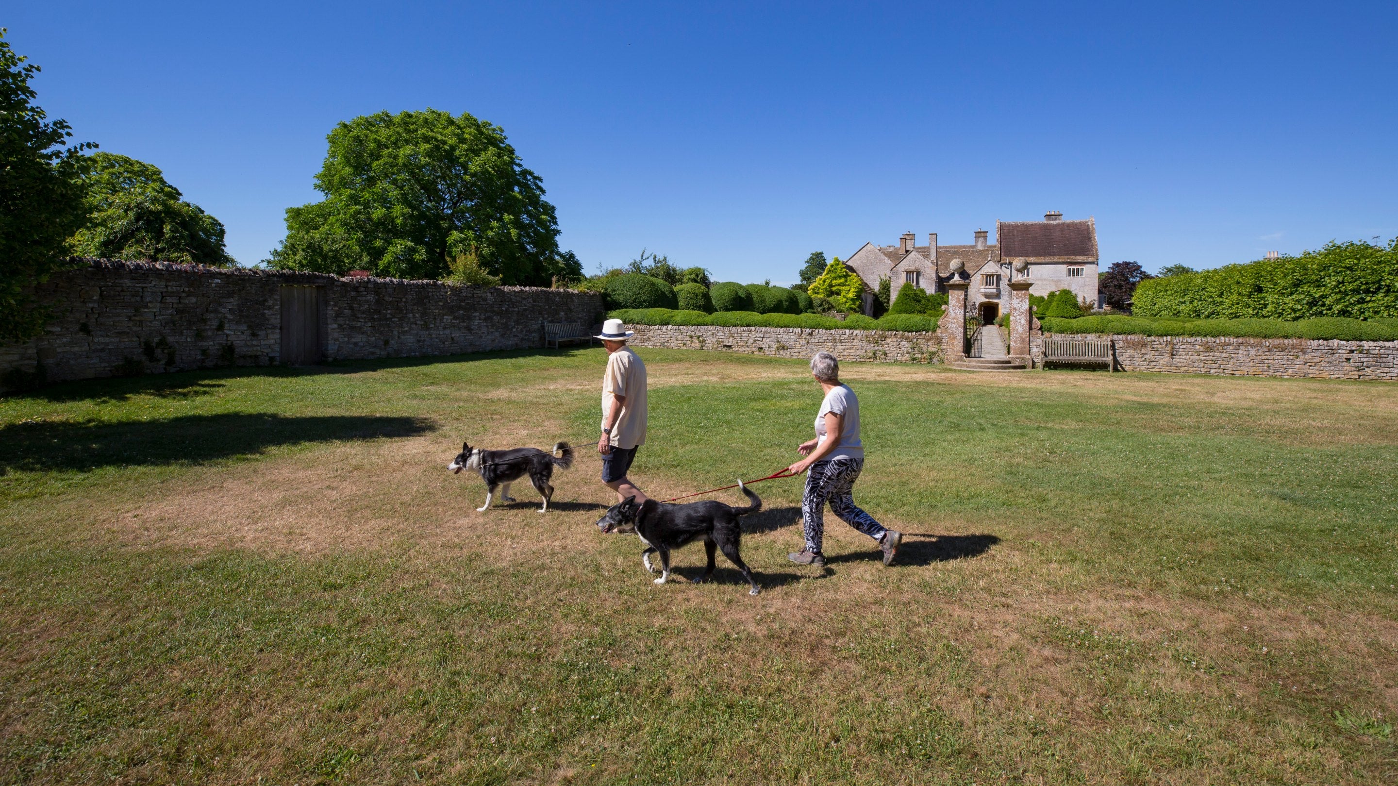 Visitors walking their dogs in the garden during the summer at Lytes Cary Manor, Somerset
