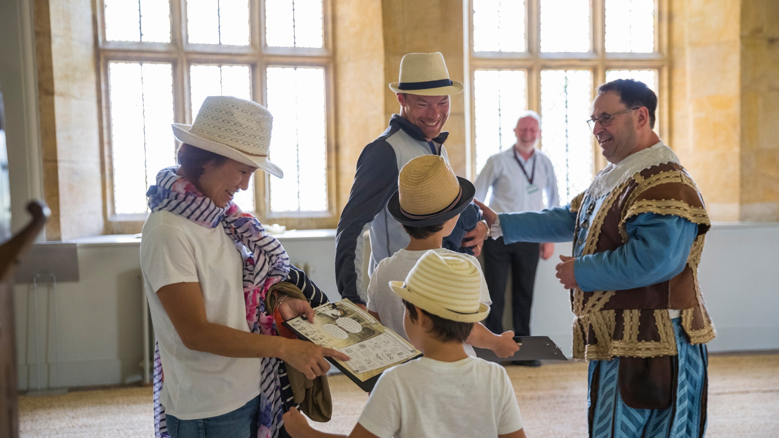 Family in hall being greeted by volunteer in medieval servants livery