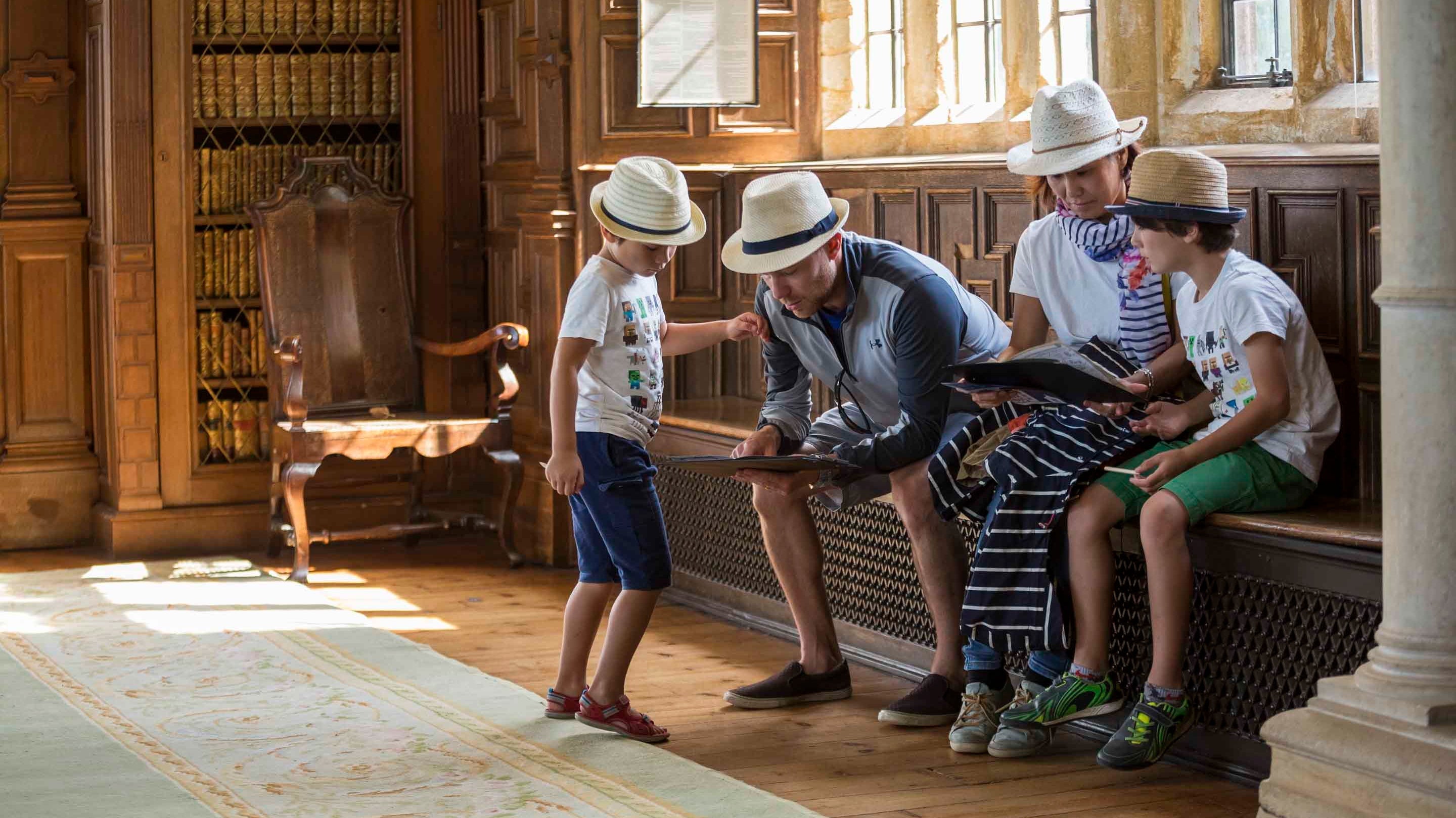 Four visitors sitting in the library at Montacute House surrounded by wood panelled walls