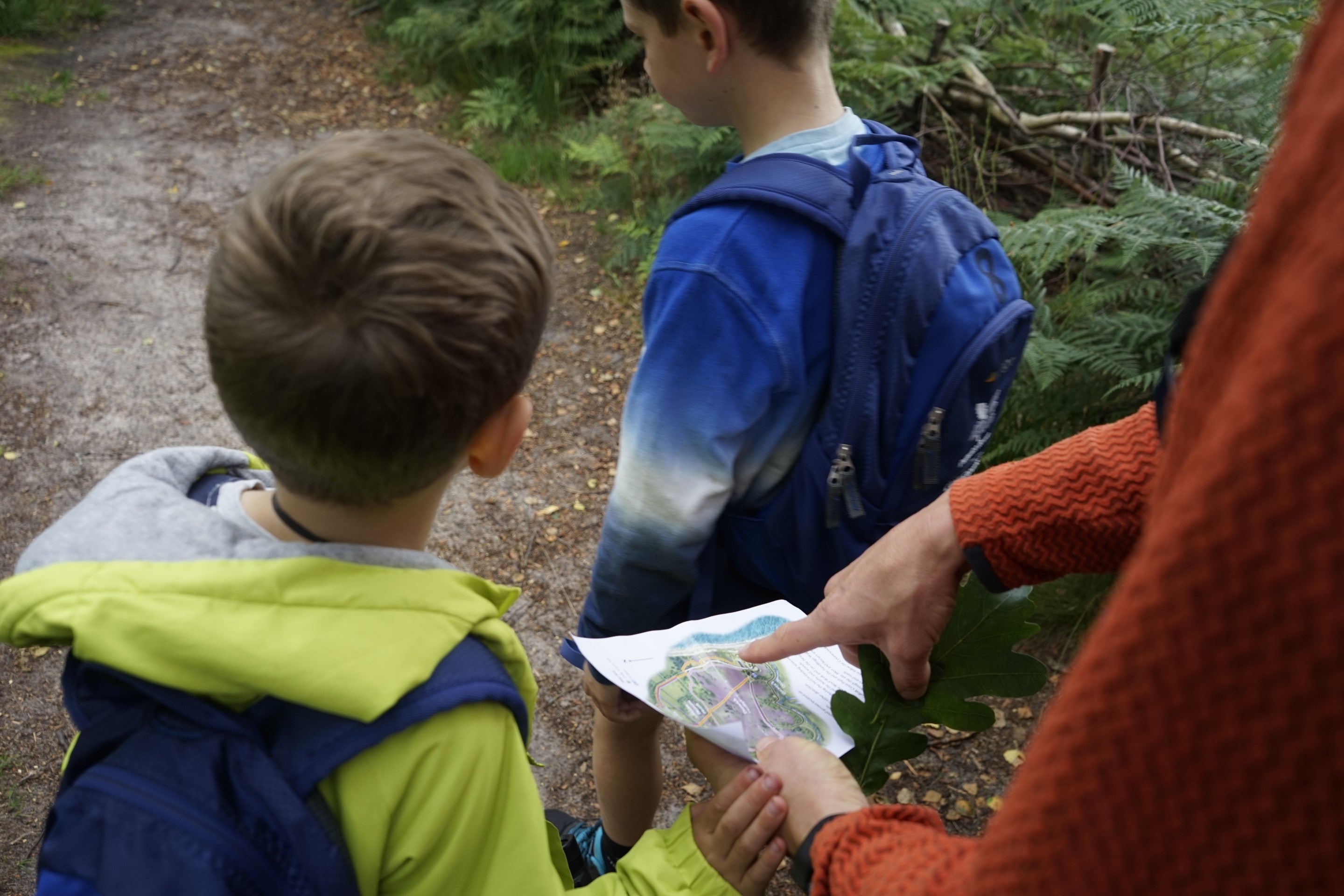 A family of two boys and their dad looking at a trail map for Dunwich Heath and Beach