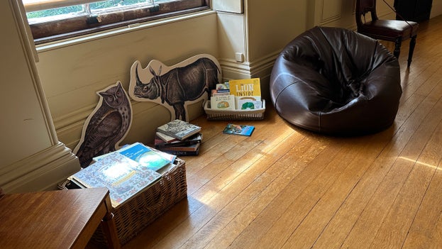 a brown beanbag on the right of the image with a basket of childrens books next to it. A chair is visible on the left hand side