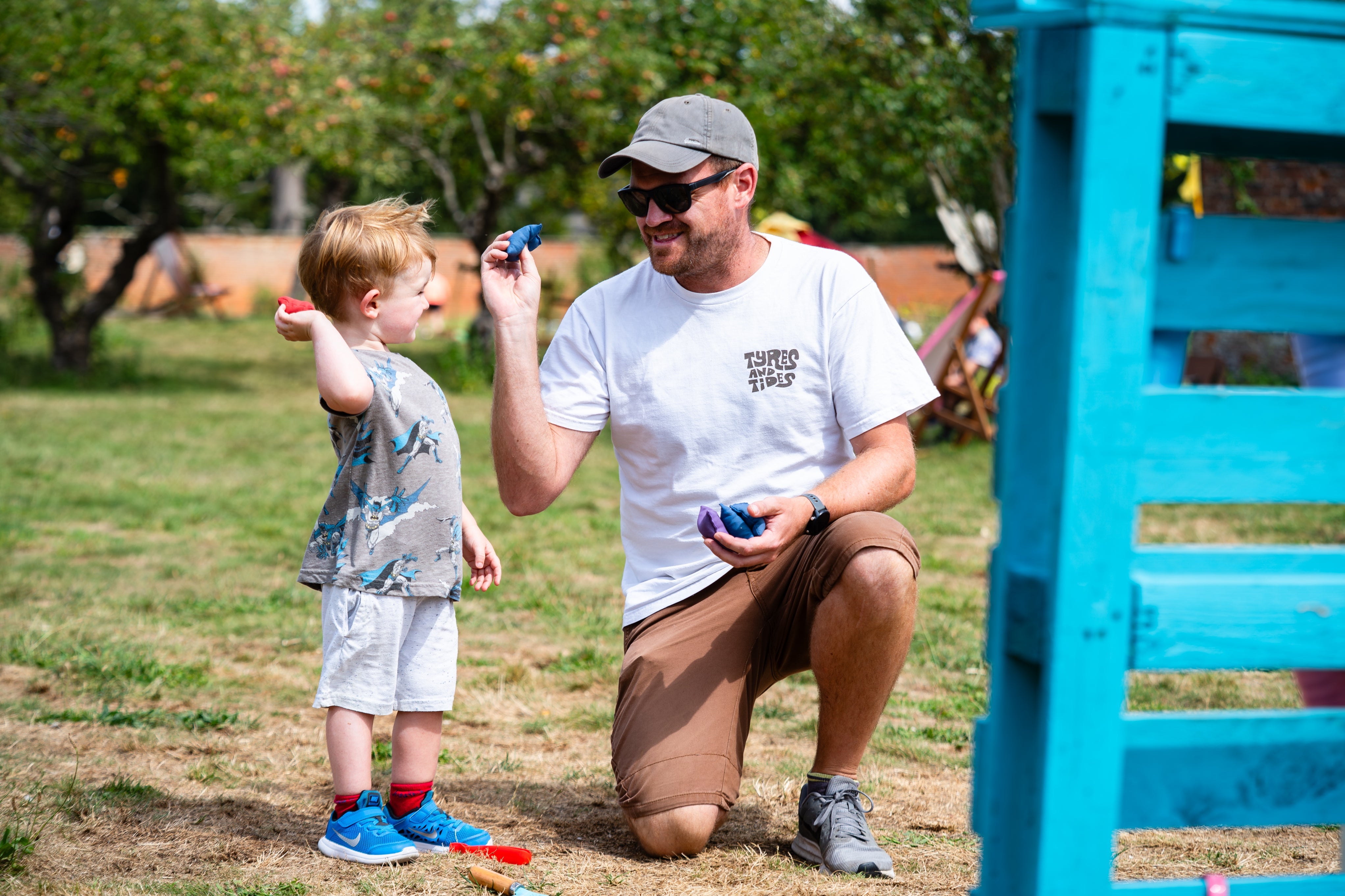 A father and son smile at each other while trying out the beanbag toss at Summer of Play