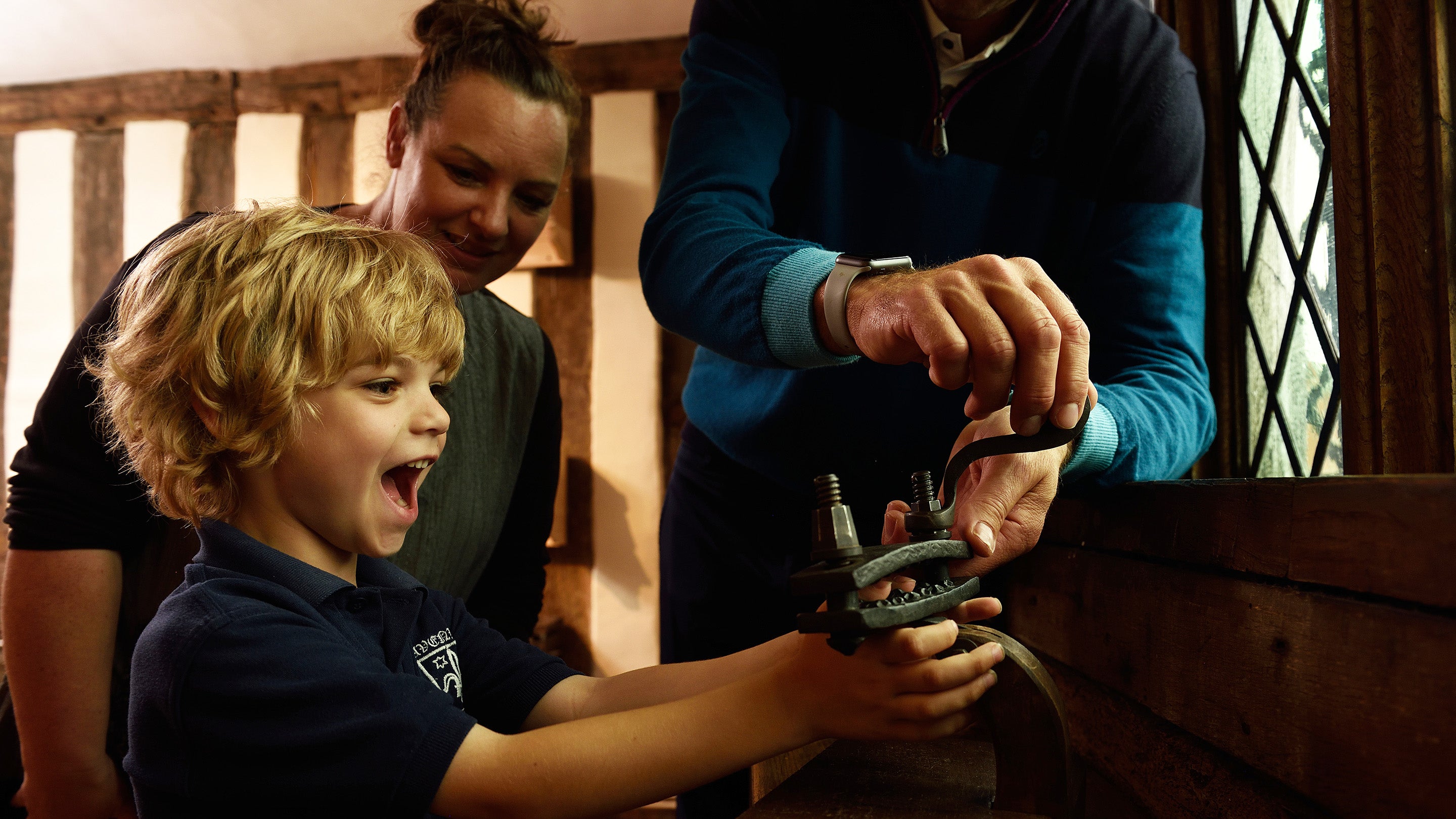 Visitors looking at a replica model of a medieval thumbscrew at Lavenham Guildhall, Suffolk